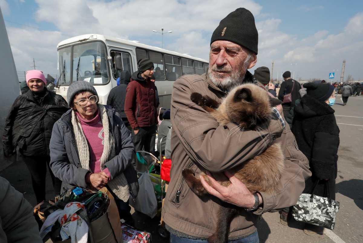 A man holds a cat as evacuees wait before boarding a bus to leave the city in the course of Ukraine-Russia conflict in the southern port of Mariupol, Ukraine April 5, 2022. REUTERS