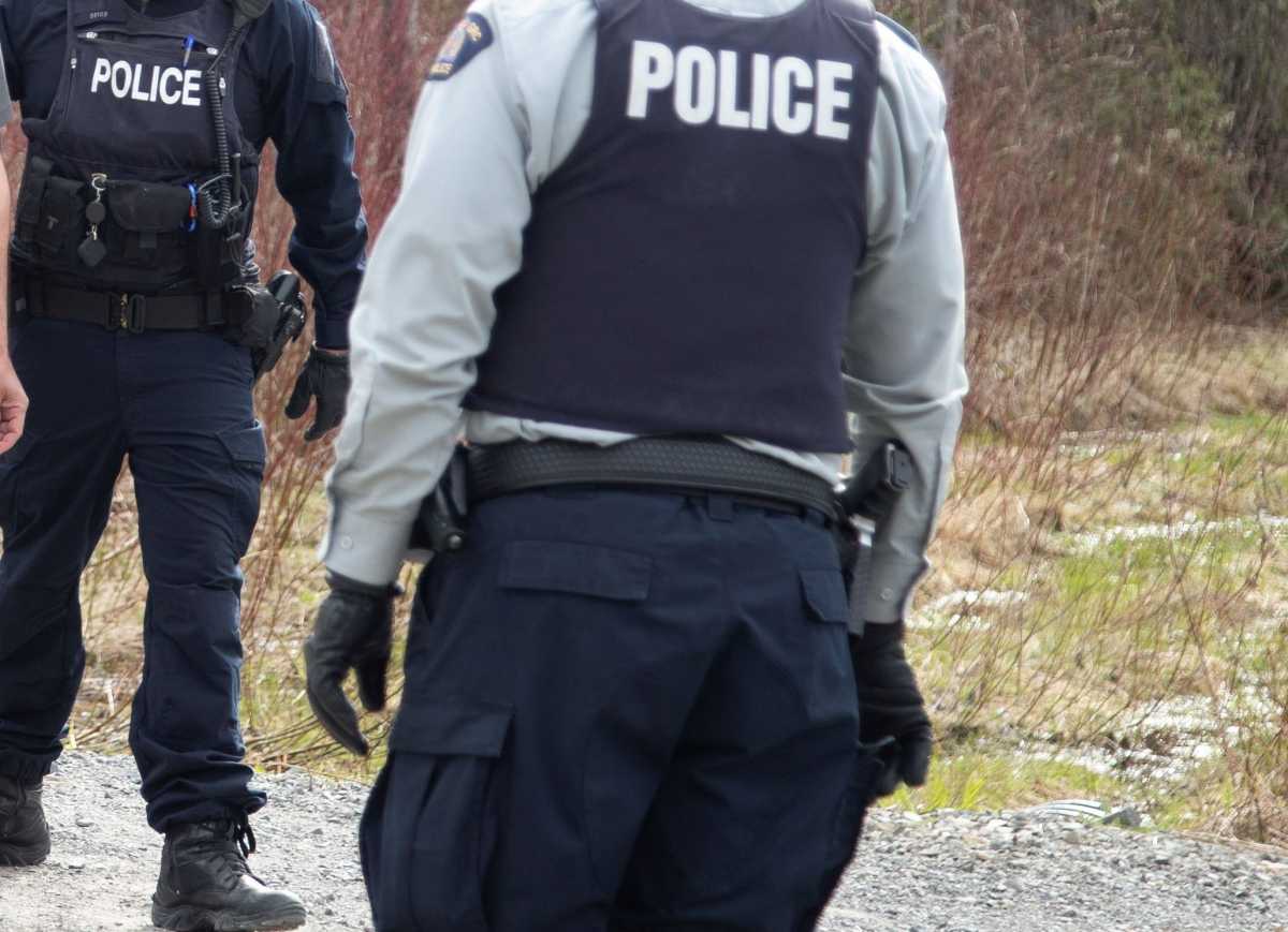 A police officer escorts an asylum seeker as he crosses into Canada from the U.S. border near a checkpoint on Roxham Road near Hemmingford, Quebec, Canada April 24, 2022. Picture taken April 24, 2022. REUTERS