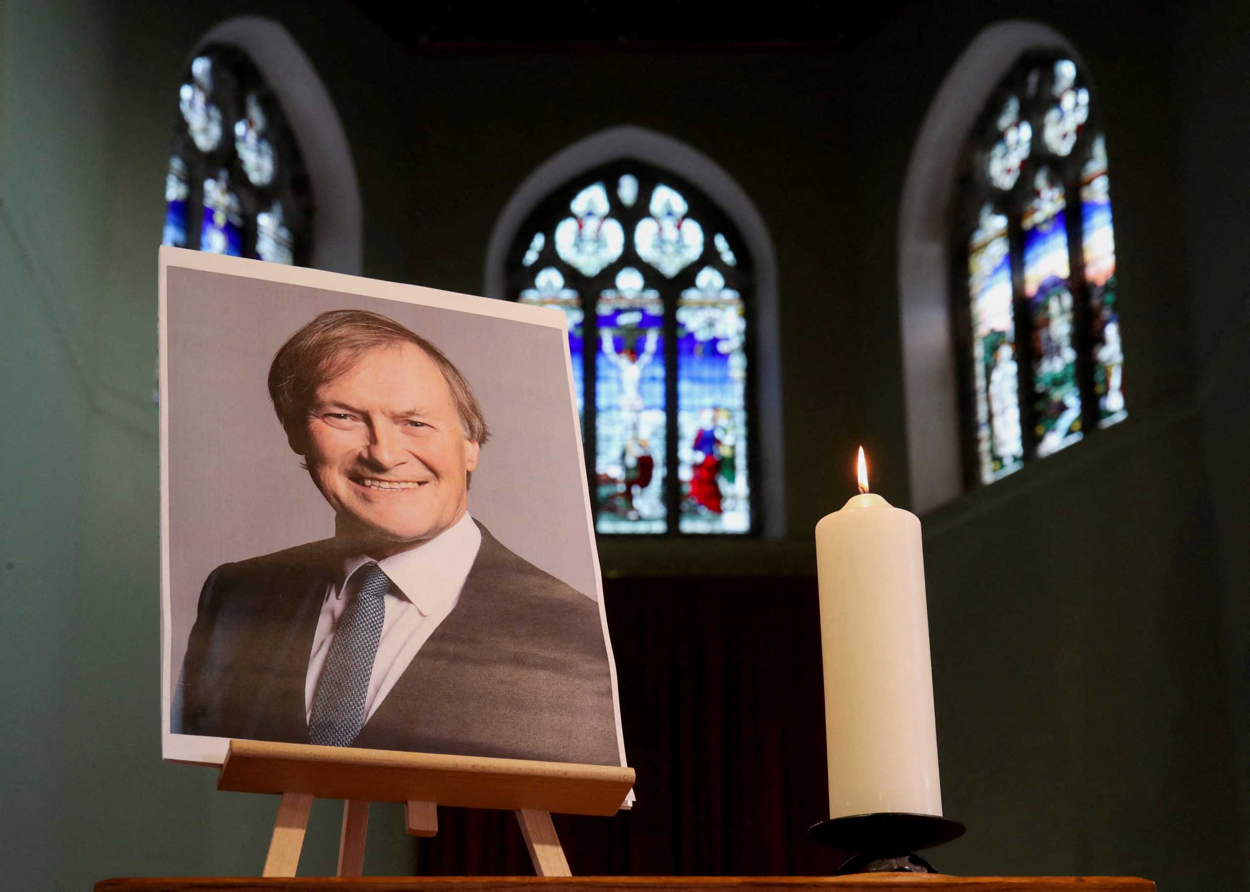 FILE PHOTO: A candle and a portrait of British MP David Amess, who was stabbed to death during a meeting with constituents, are seen at the church of St Michael's and all Angels, in Leigh-on-Sea, Britain, October 17, 2021. REUTERS