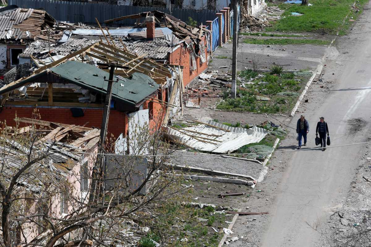 People walk near buildings damaged in the course of Ukraine-Russia conflict in the southern port city of Mariupol, Ukraine April 18, 2022. REUTERS