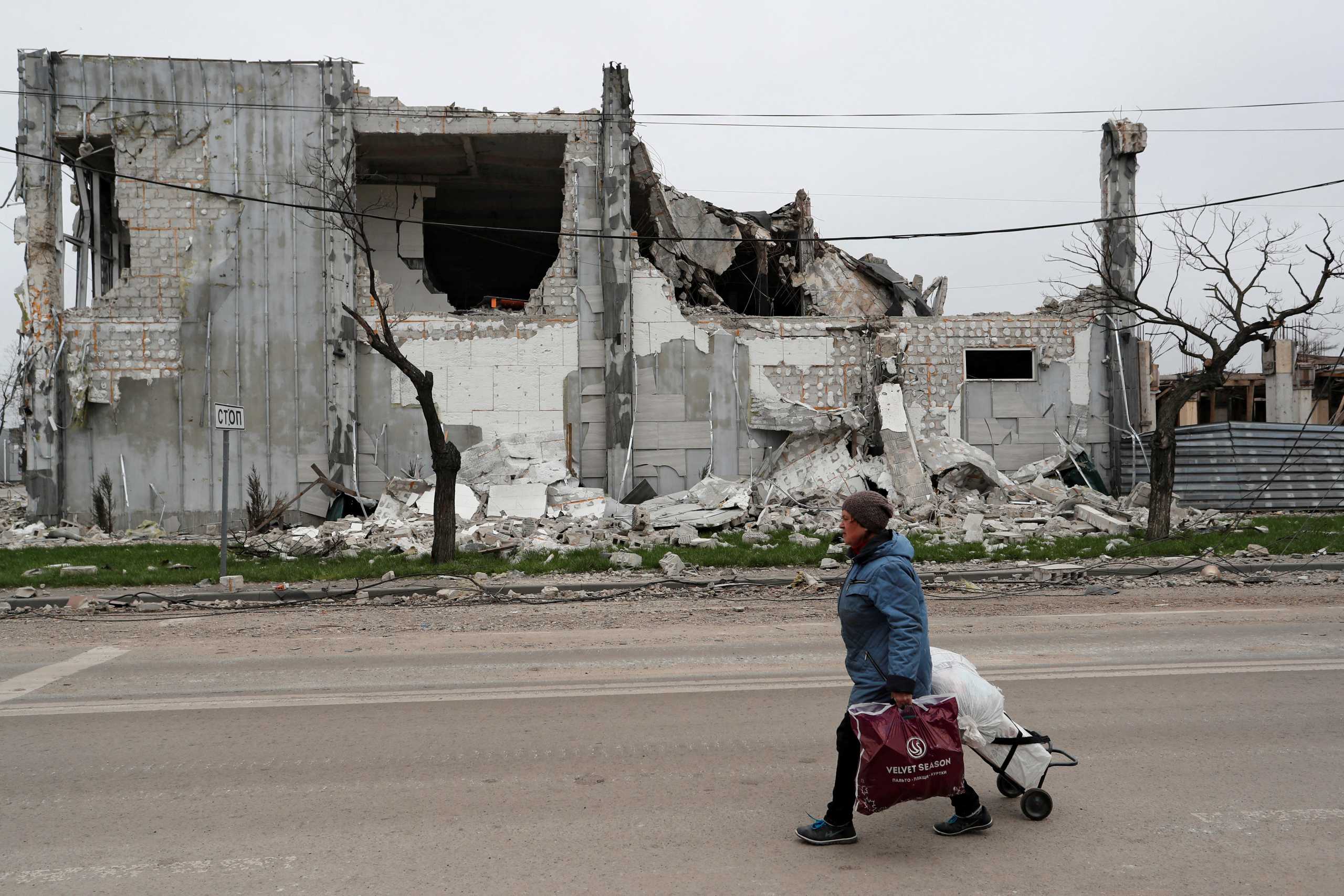 FILE PHOTO: A local resident walks past a building destroyed during Ukraine-Russia conflict in the southern port city of Mariupol, Ukraine April 19, 2022. REUTERS