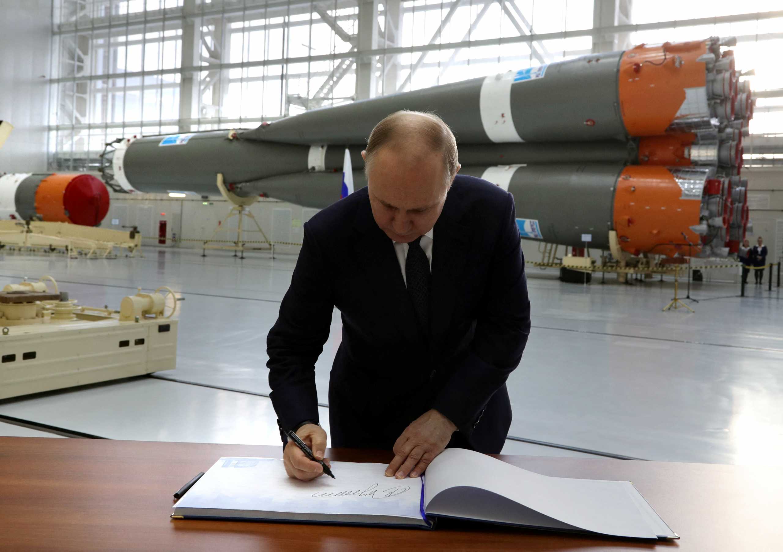 Russian President Vladimir Putin signs distinguished visitors' book in an assembly and test facility at the Vostochny Cosmodrome in Amur Region, Russia April 12, 2022. Sputnik