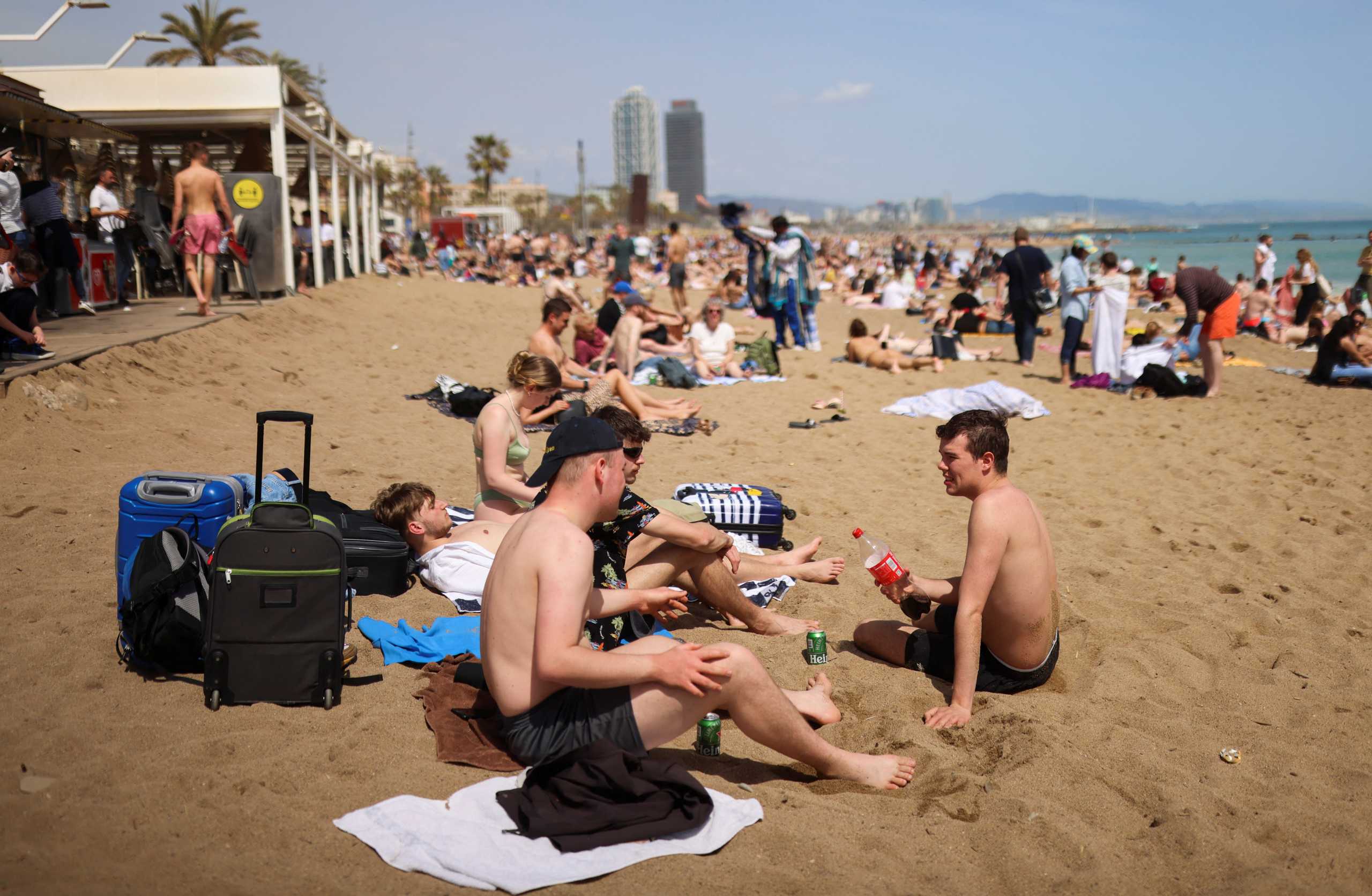 Tourists enjoy the sunny weather next to their lugagge at the Barceloneta beach, as Spain expects Easter bounce to lift tourism to 80 percent of pre-coronavirus disease (COVID-19) levels, in Barcelona, Spain, April 15, 2022. REUTERS