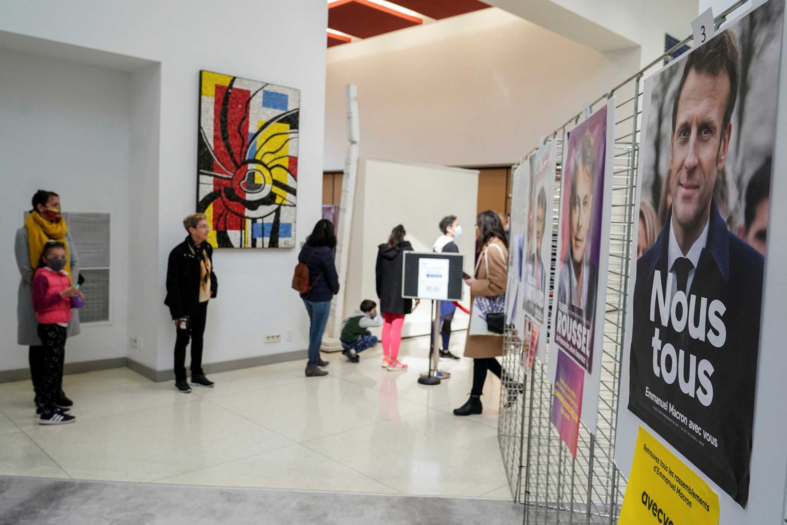 French citizens stand in line near campaign posters as they arrive to vote in the French elections at the French Embassy in Washington, U.S., April 9, 2022. REUTERS