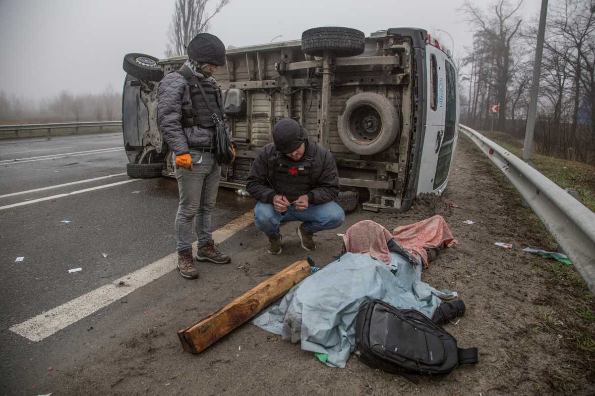 SENSITIVE MATERIAL. THIS IMAGE MAY OFFEND OR DISTURB A volunteer inspects a body of killed person, as Russia's attack on Ukraine continues, on a street in the town of Bucha, in Kyiv region, Ukraine April 1, 2022. REUTERS