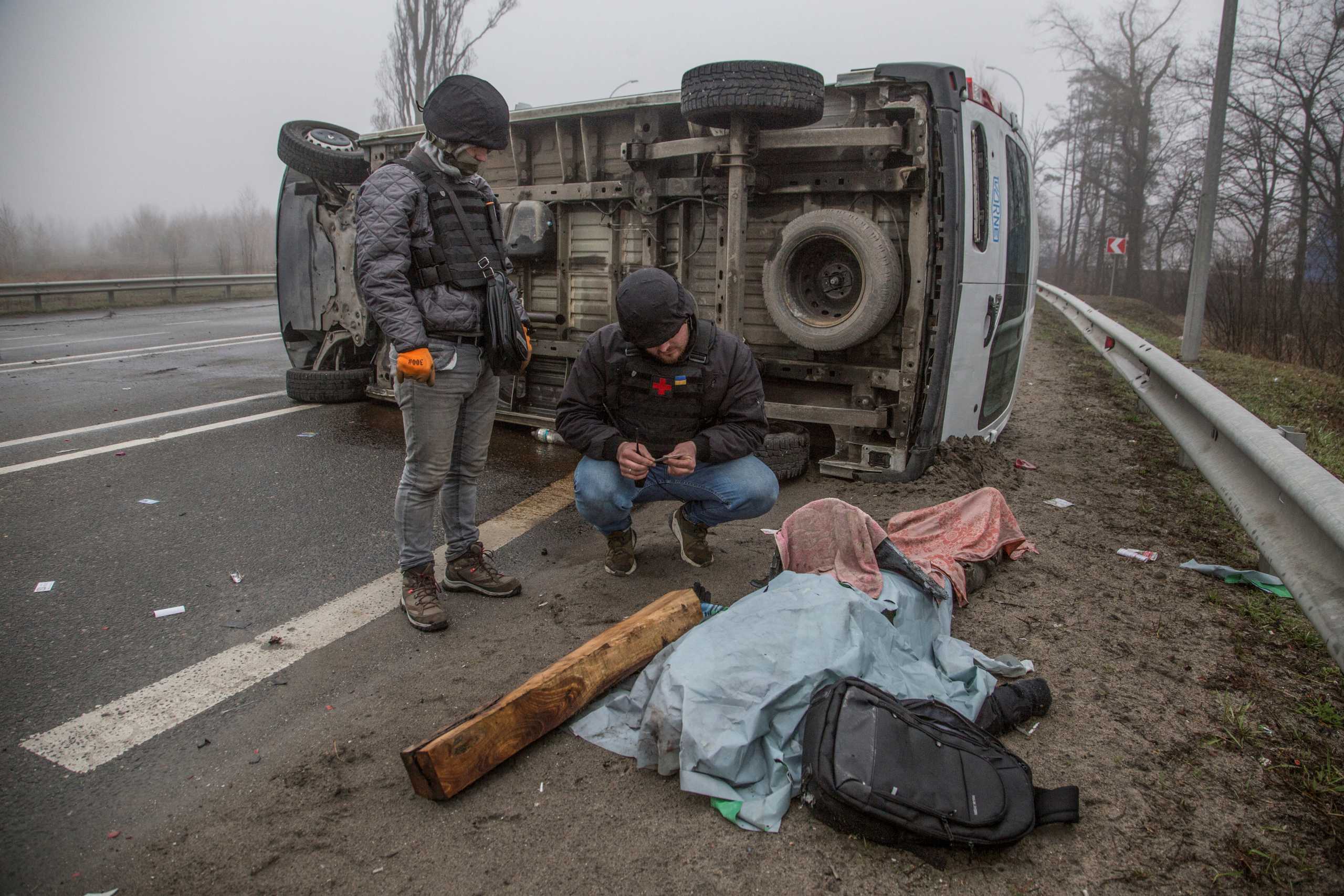 SENSITIVE MATERIAL. THIS IMAGE MAY OFFEND OR DISTURB A volunteer inspects a body of killed person, as Russia's attack on Ukraine continues, on a street in the town of Bucha, in Kyiv region, Ukraine April 1, 2022. REUTERS