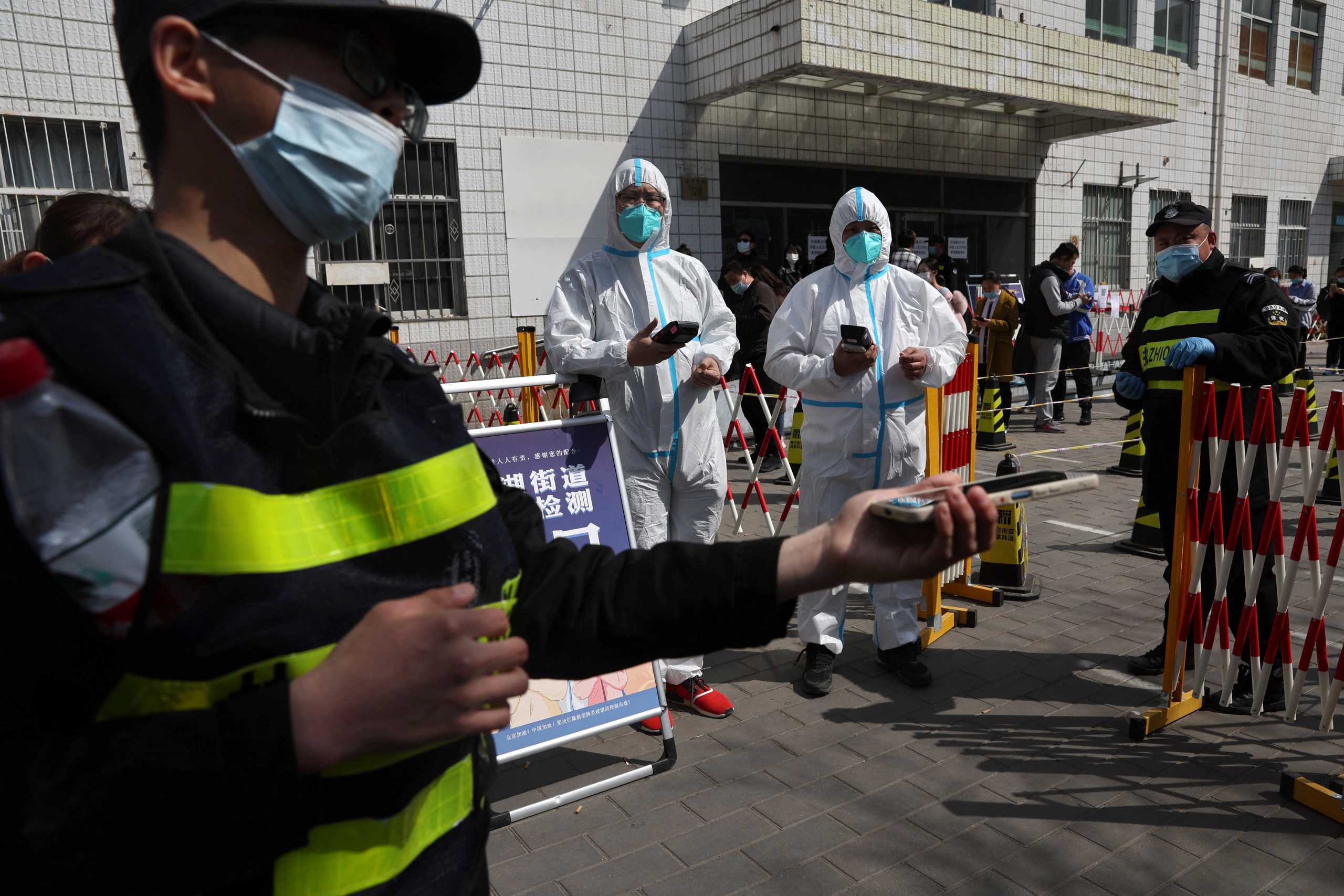 Workers in protective suits check registration codes as people enter a nucleic acid testing site, following the coronavirus disease (COVID-19) outbreak, in Beijing, China April 6, 2022. REUTERS