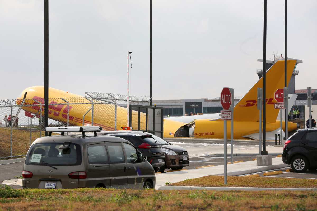 Airport personnel stand at the scene where a Boeing 757-200 cargo aircraft operated by DHL made an emergency landing before skidding off the runway and splitting, aviation authorities said, at the Juan Santamaria International Airport in Alajuela, Costa Rica April 7, 2022. REUTERS