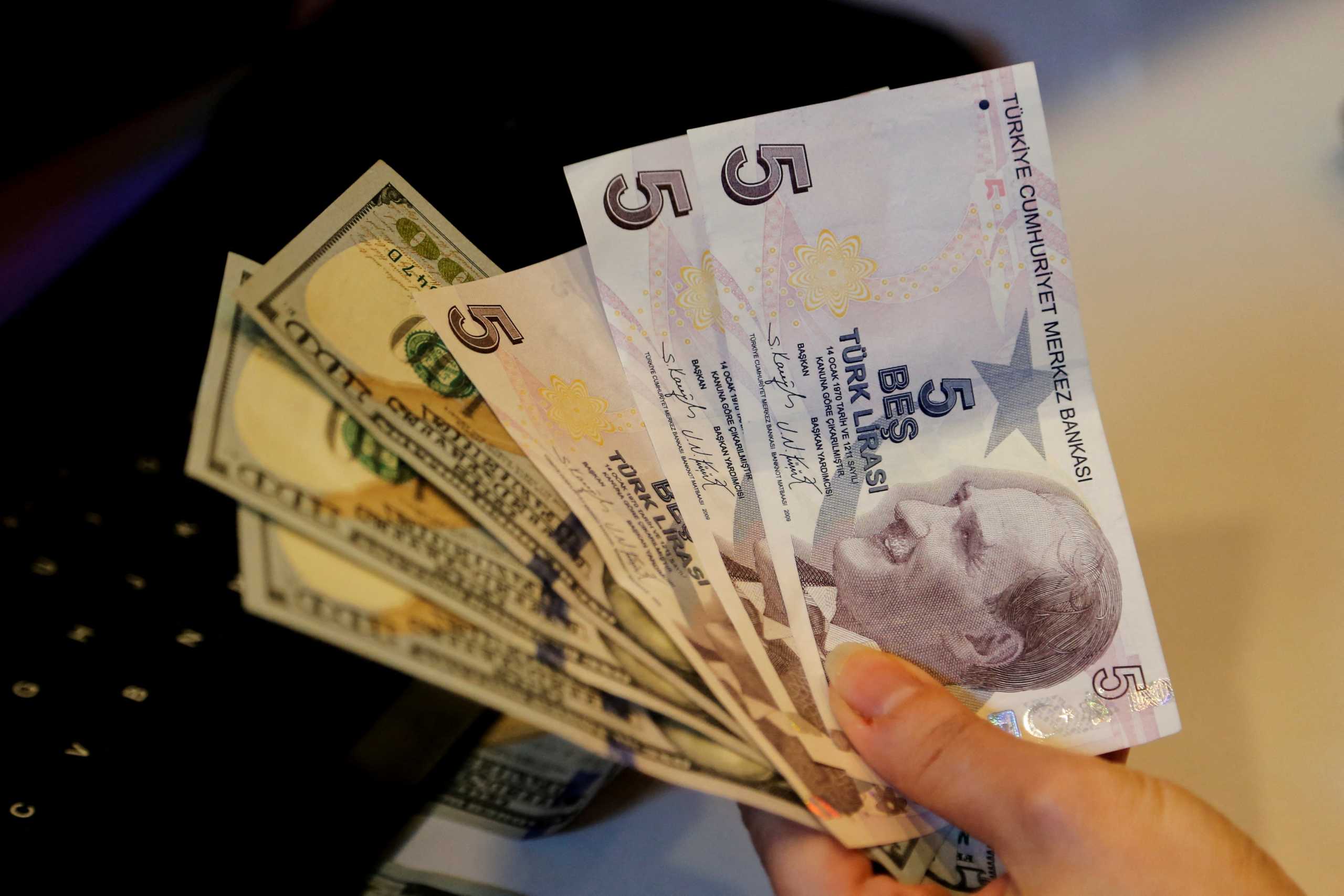 FILE PHOTO: A money changer holds Turkish lira  and U.S. dollar banknotes at a currency exchange office in Ankara, Turkey December 16, 2021. REUTERS
