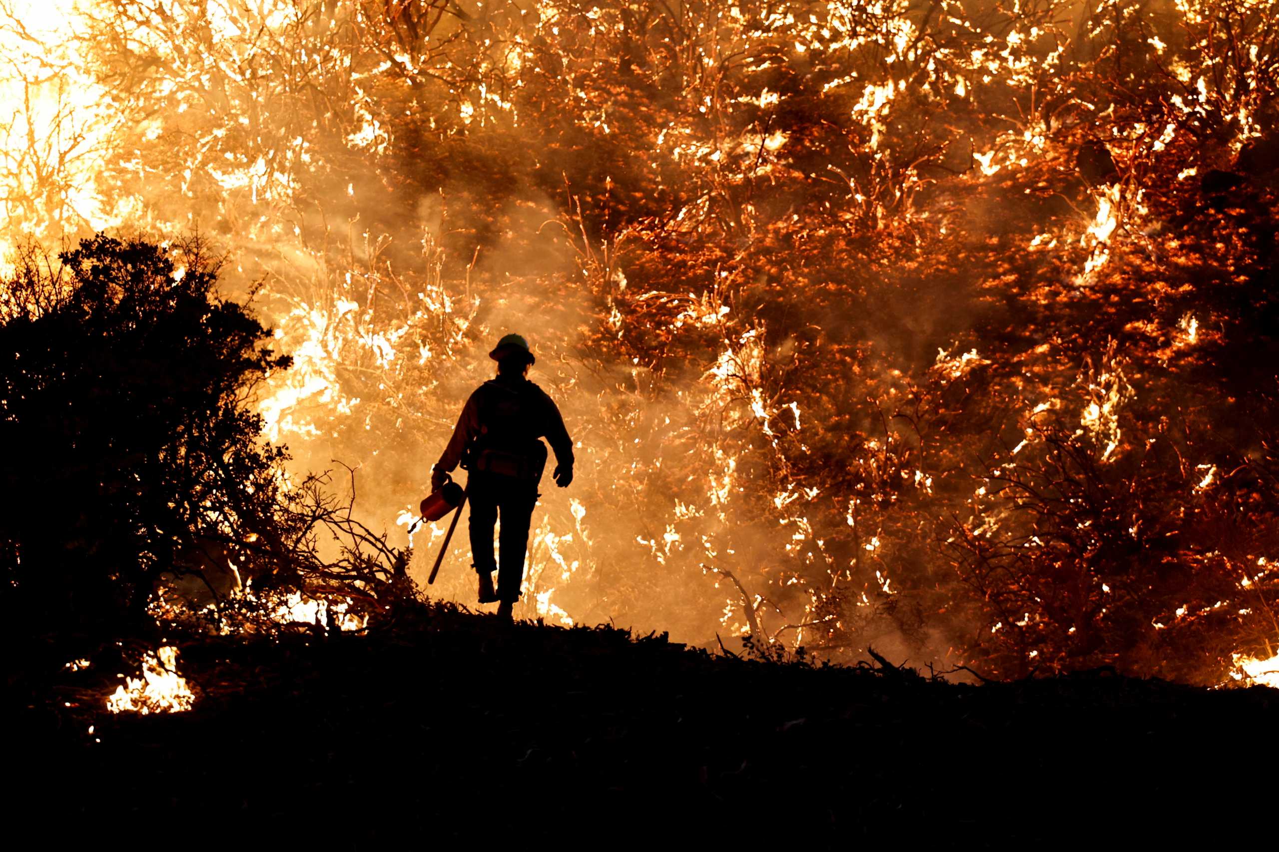 FILE PHOTO: A firefighter works as the Caldor Fire burns in Grizzly Flats, California, U.S., August 22, 2021.REUTERS