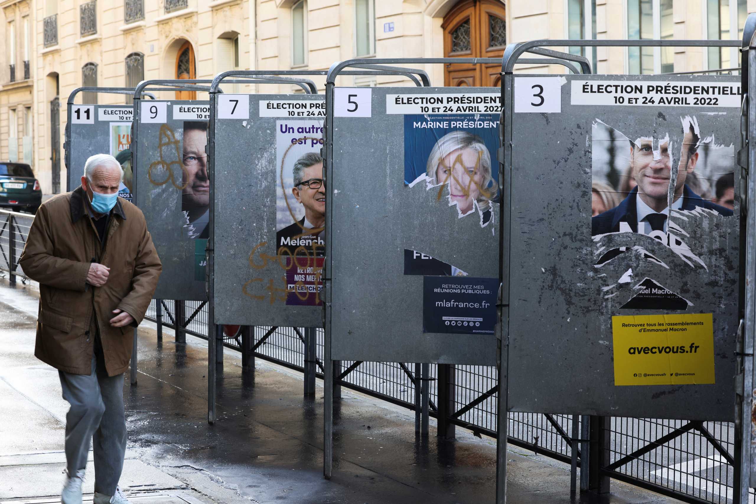 A man walks past torn campaign posters of candidates in the 2022 French presidential election, on bulletin boards near a polling station, during the first round of the 2022 French presidential election, in Paris, France, April 10, 2022. REUTERS