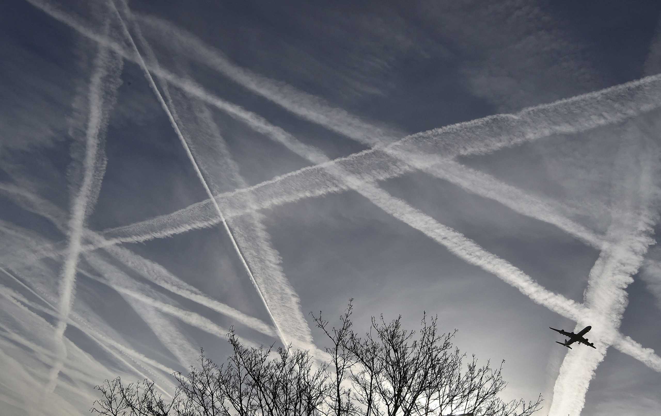 FILE PHOTO: A passenger plane flies through aircraft contrails in the skies near Heathrow Airport in west London, April 12, 2015. REUTERS