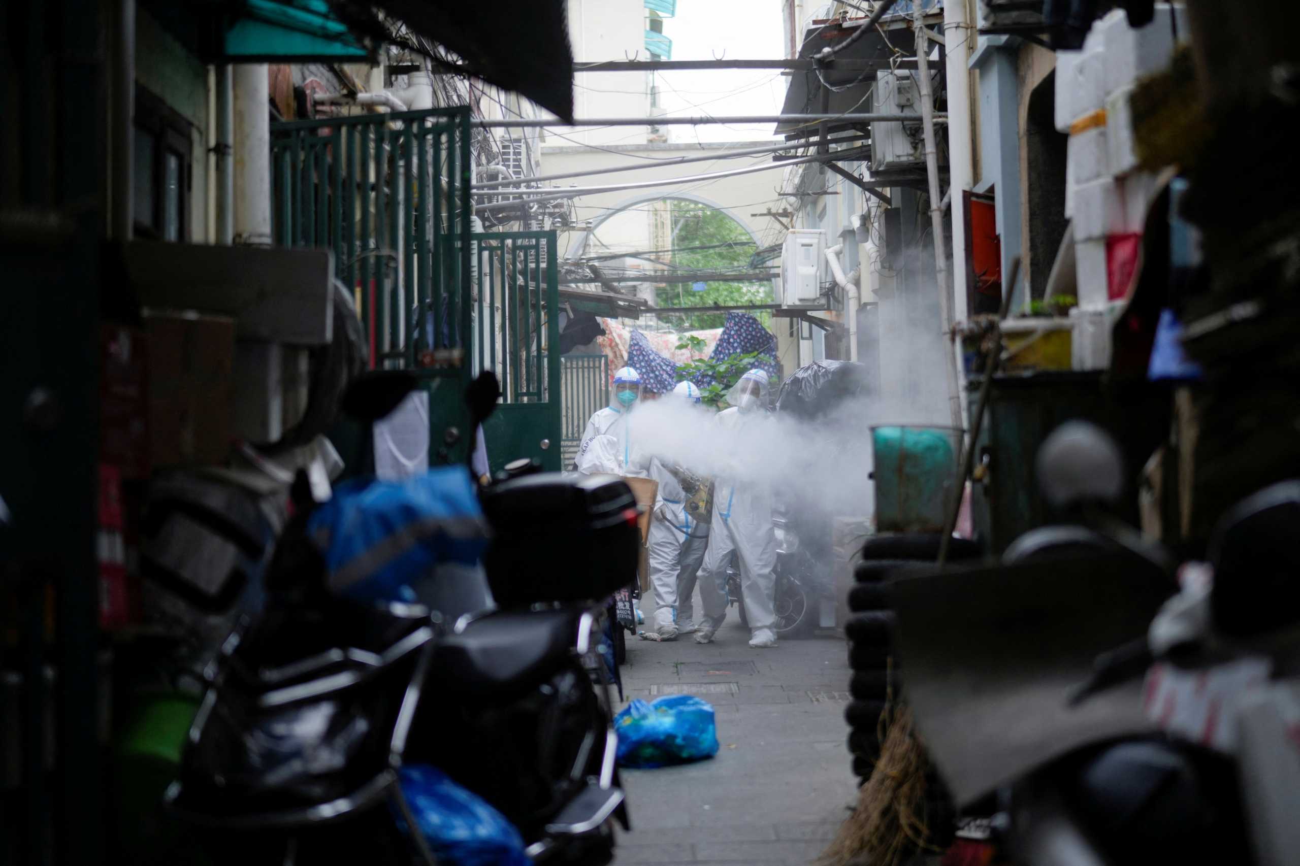 Workers in protective suits disinfect an old residential area under lockdown amid the coronavirus disease (COVID-19) pandemic, in Shanghai, China, April 15, 2022. REUTERS