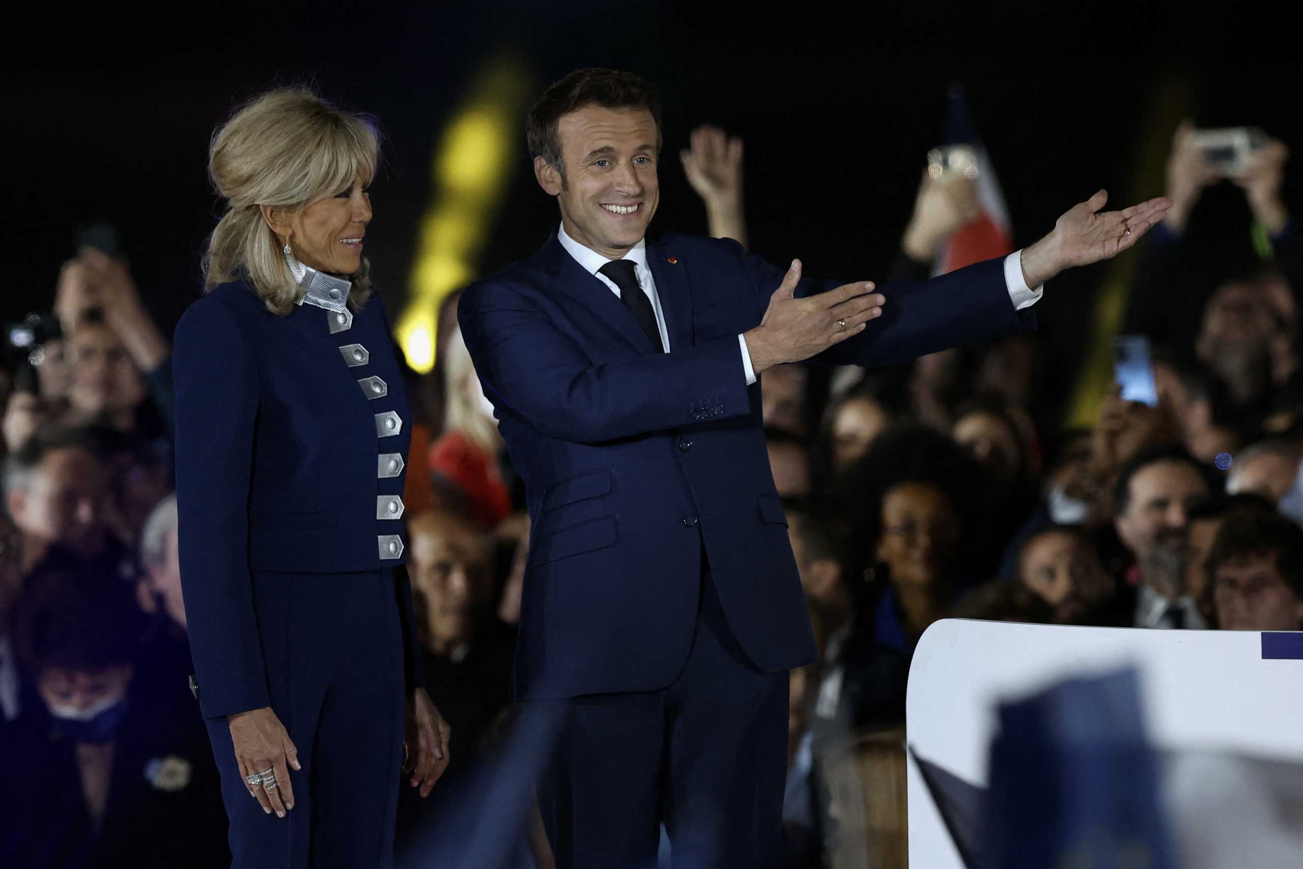 French President Emmanuel Macron gestures on stage next to his wife, French first lady Brigitte Macron,  after being re-elected as president, following the results in the second round of the 2022 French presidential election, during his victory rally at the Champ de Mars in Paris, France, April 24, 2022. REUTERS