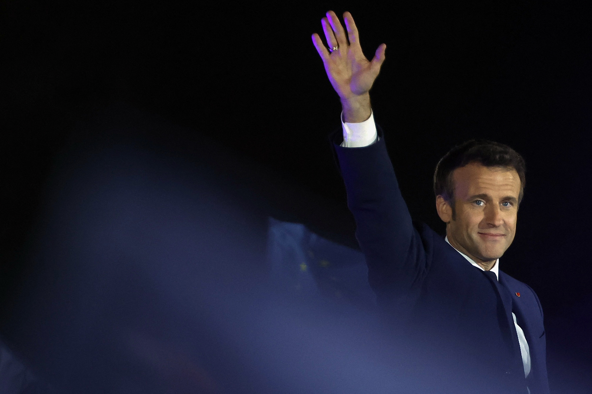 French President Emmanuel Macron waves on stage after being re-elected as president, following the results in the second round of the 2022 French presidential election, during his victory rally at the Champ de Mars in Paris, France, April 24, 2022. REUTERS