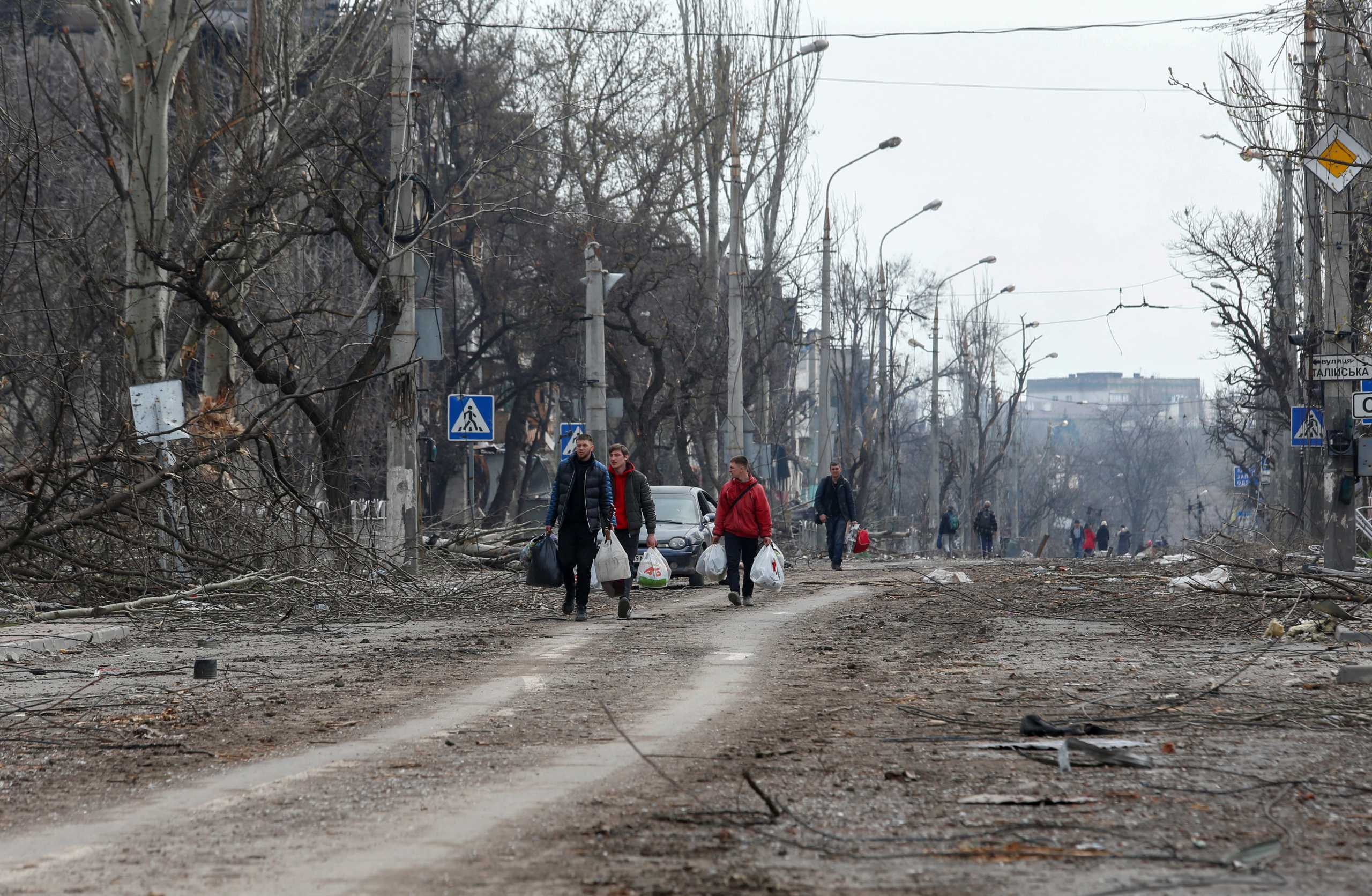 People walk along a street, which was damaged during Ukraine-Russia conflict in the southern port city of Mariupol, Ukraine April 17, 2022. REUTERS