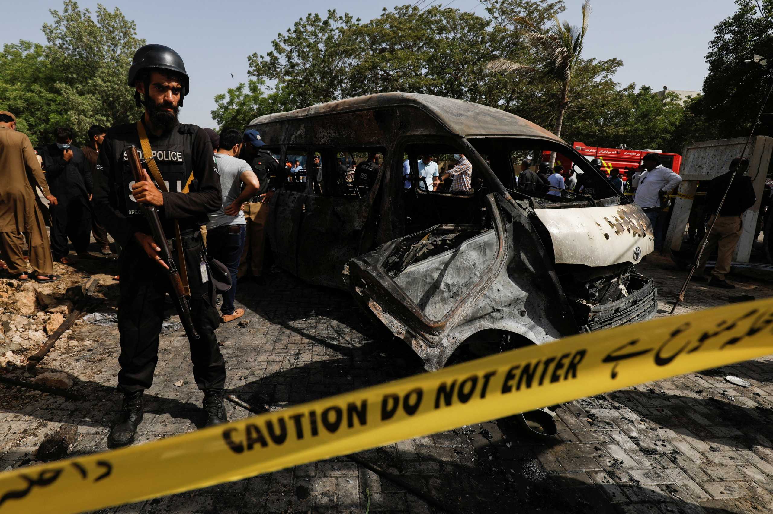 A police officer stands guard near a passenger van, cordoned after a blast at the entrance of the Confucius Institute University of Karachi, Pakistan, April 26, 2022. REUTERS