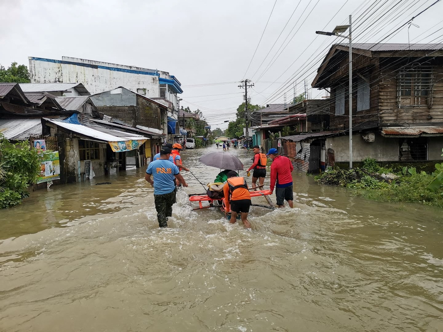 Rescuers push a woman in a raft on a flooded road, after the tropical storm Megi hit, in Leyte Province, Philippines April 10, 2022. Picture taken April 10, 2022. Philippine Coast Guard