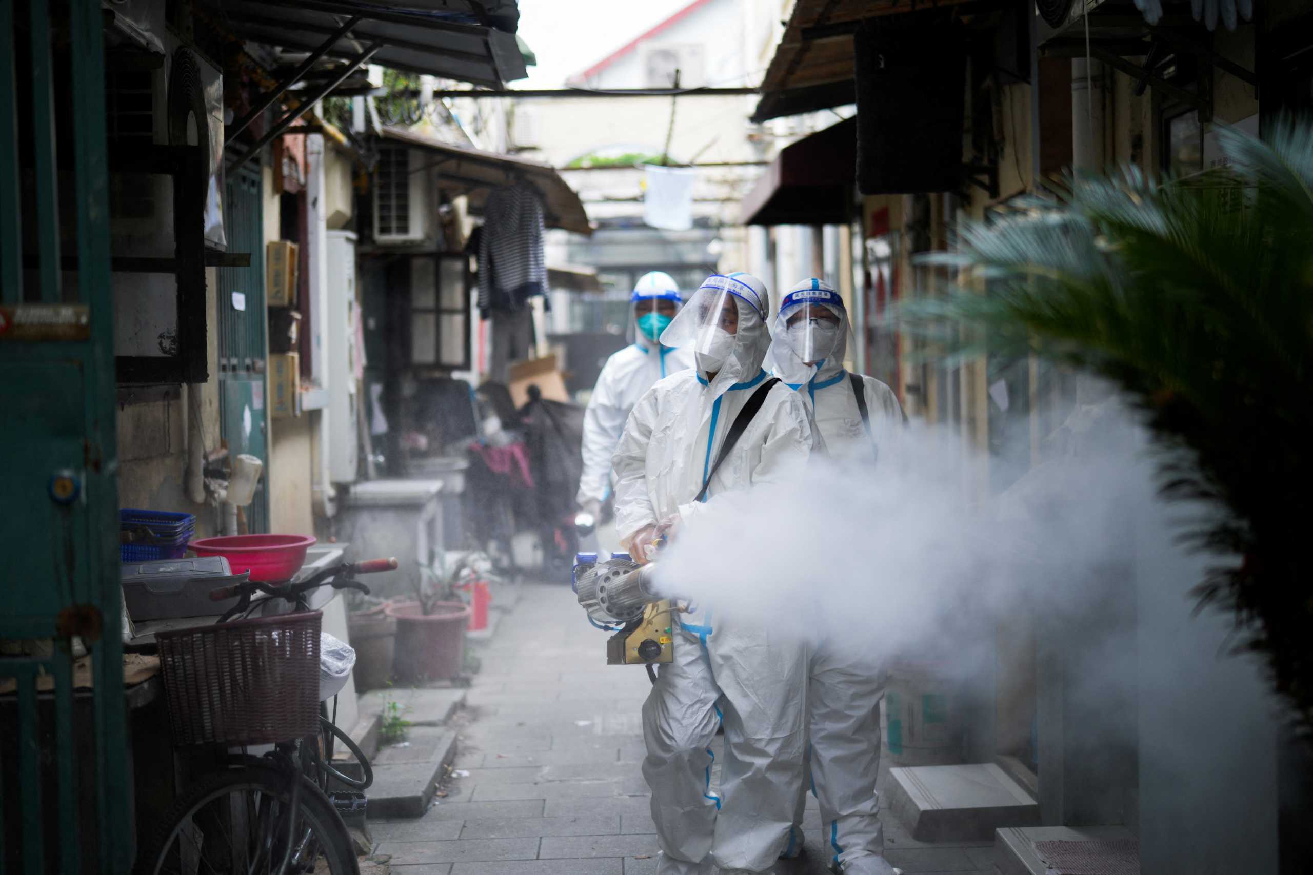 Workers in protective suits disinfect an old residential area under lockdown amid the coronavirus disease (COVID-19) pandemic, in Shanghai, China, April 15, 2022. REUTERS