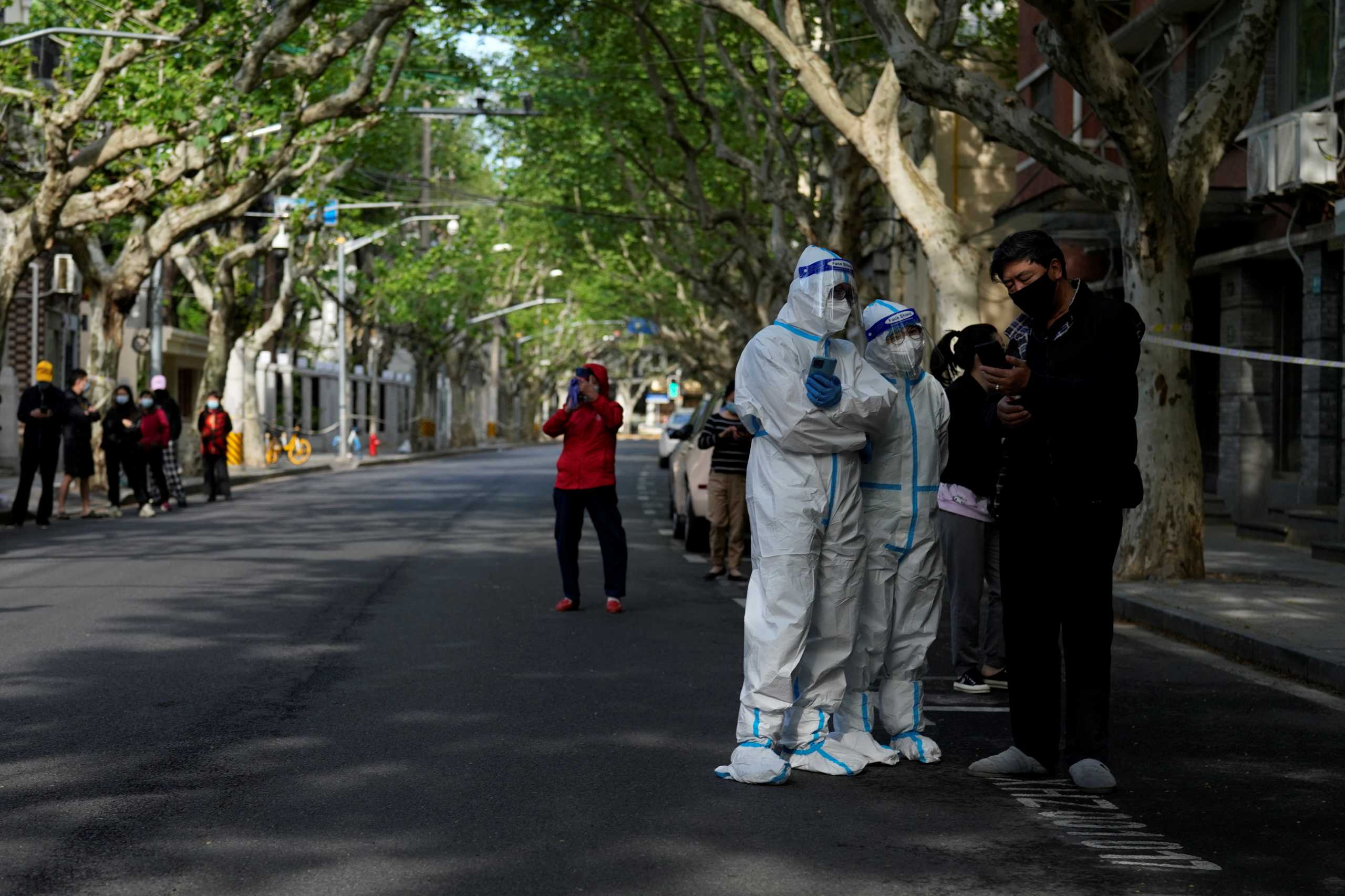 Workers in a protective suits direct residents lining up for nucleic acid test during lockdown amid the coronavirus disease (COVID-19) pandemic, in Shanghai, China, April 17, 2022. REUTERS