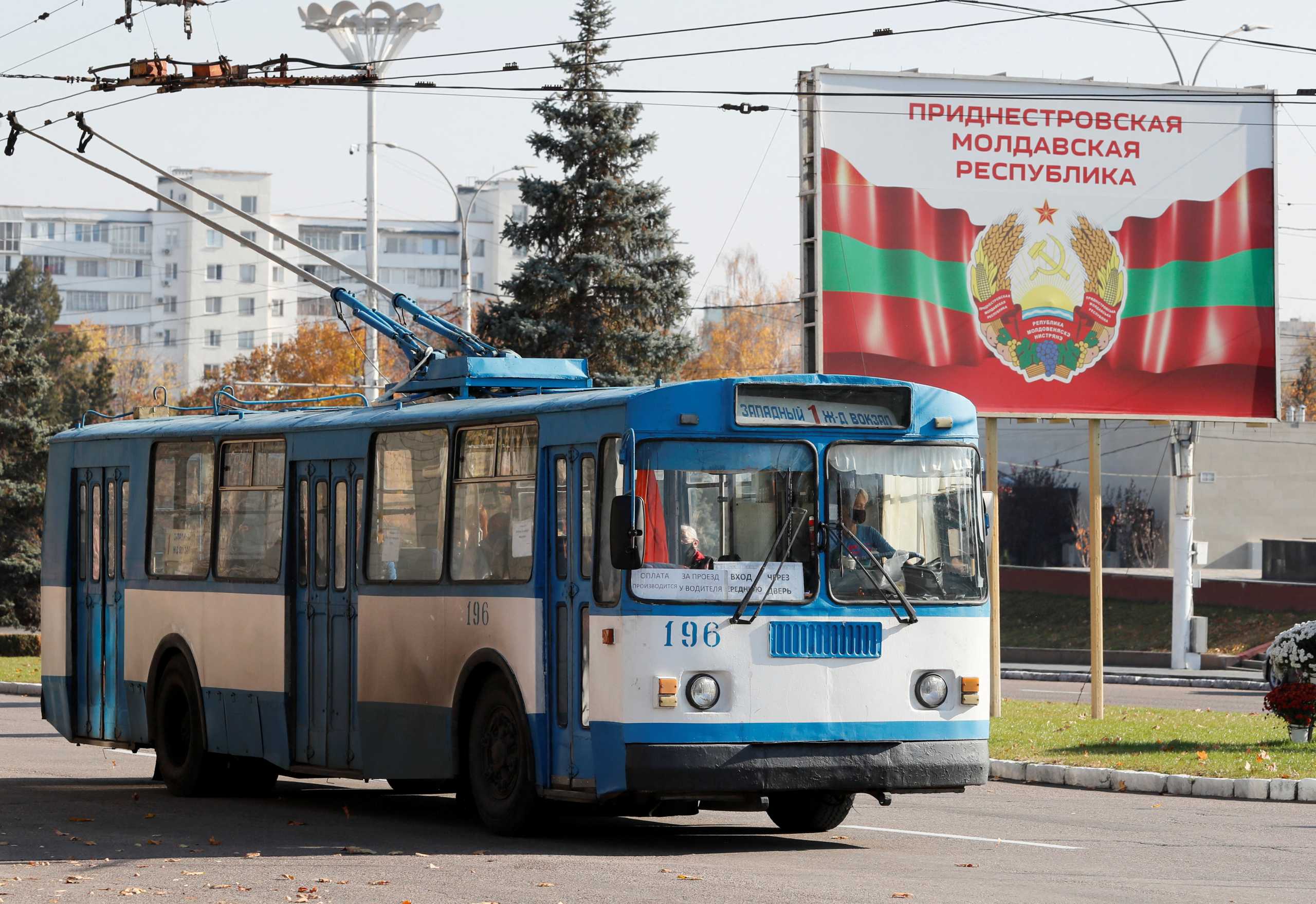 FILE PHOTO: An old trolleybus rides near a poster with the official coat of arms in Tiraspol, in Moldova's self-proclaimed separatist Transdniestria, November 3, 2021.  REUTERS