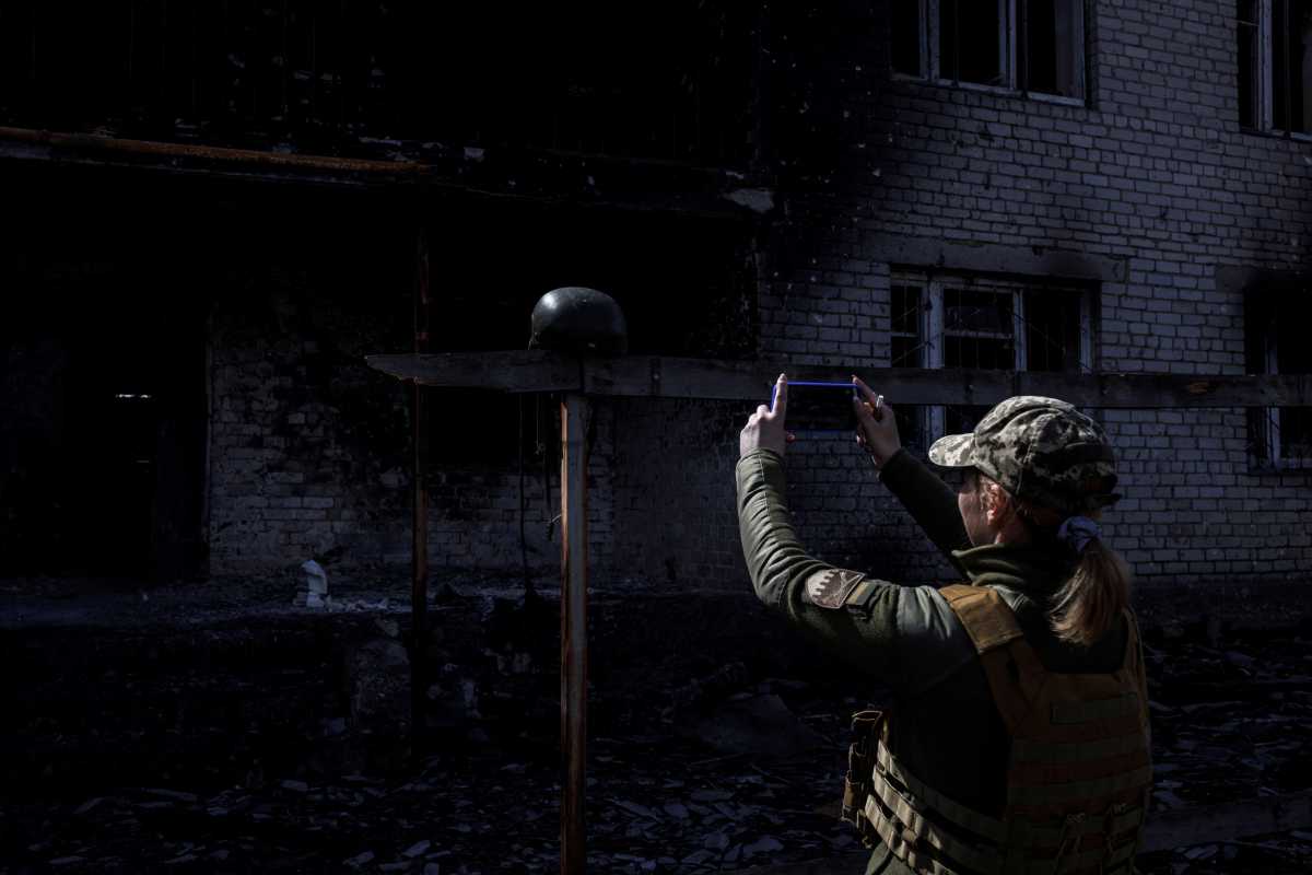 A Ukrainian soldier takes a photo of a helmet, outside a destroyed building that was used as a temporary base by the Russian army, in the village of Malaya Rohan, as Russia's attack on Ukraine continues, in the Kharkiv region, Ukraine, April 9, 2022. REUTERS