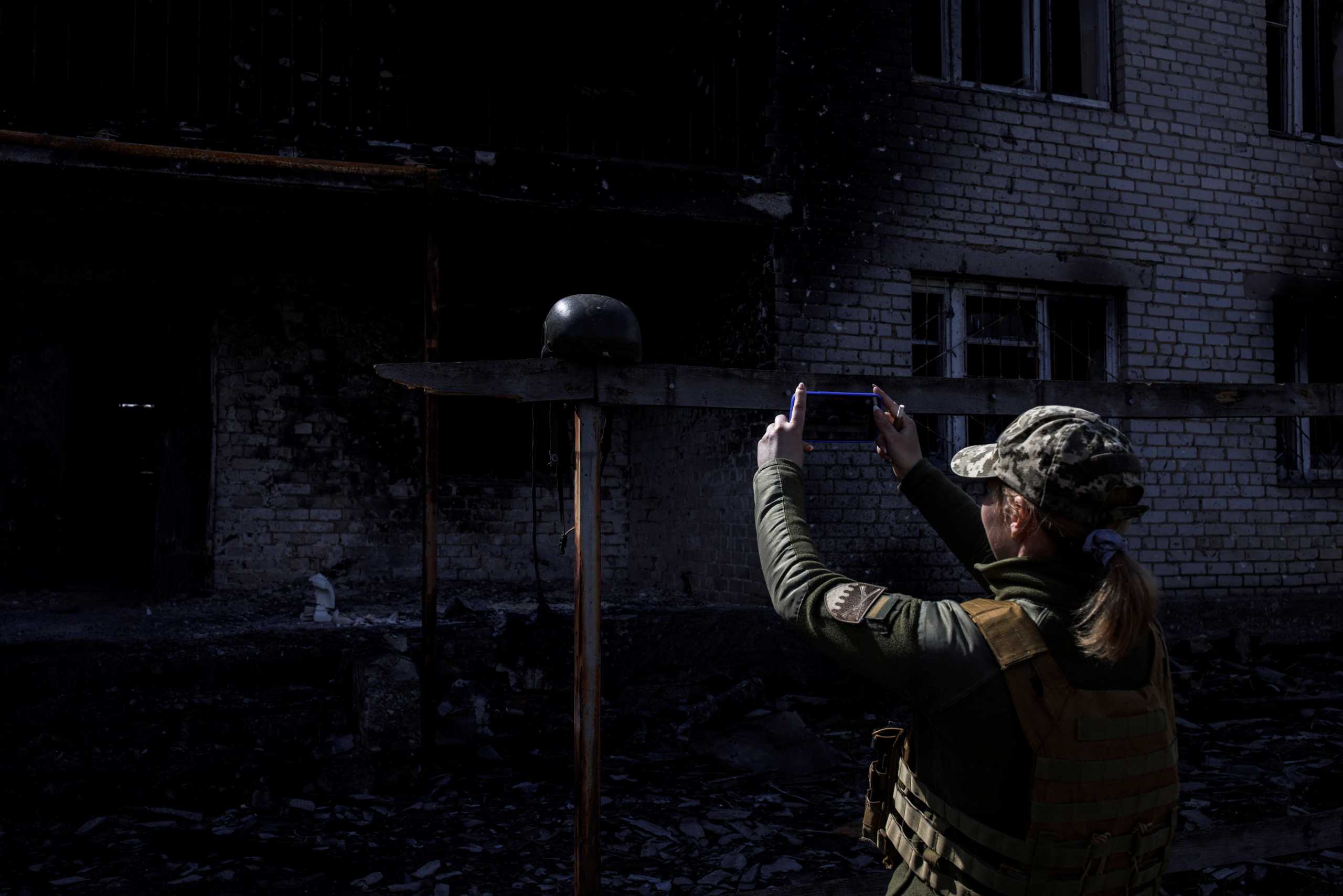 A Ukrainian soldier takes a photo of a helmet, outside a destroyed building that was used as a temporary base by the Russian army, in the village of Malaya Rohan, as Russia's attack on Ukraine continues, in the Kharkiv region, Ukraine, April 9, 2022. REUTERS