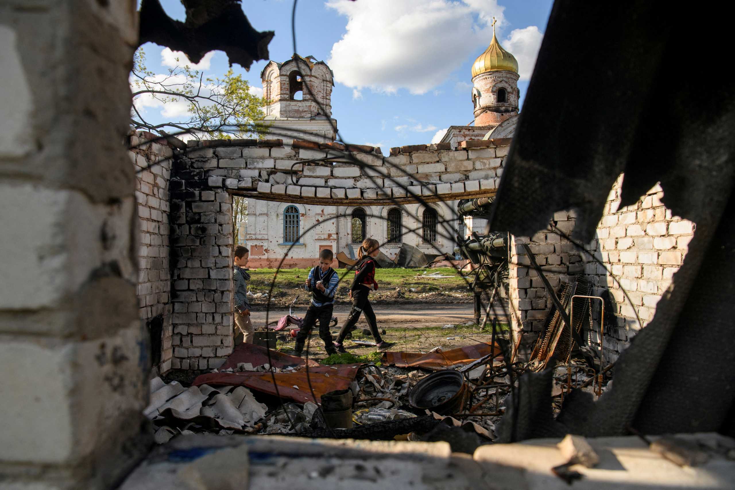 Local boys Faddei and Oleksandr play in front of a church damaged during Russia's invasion of Ukraine, in the village of Kolychivka, in Chernihiv region, Ukraine April 27, 2022.  REUTERS