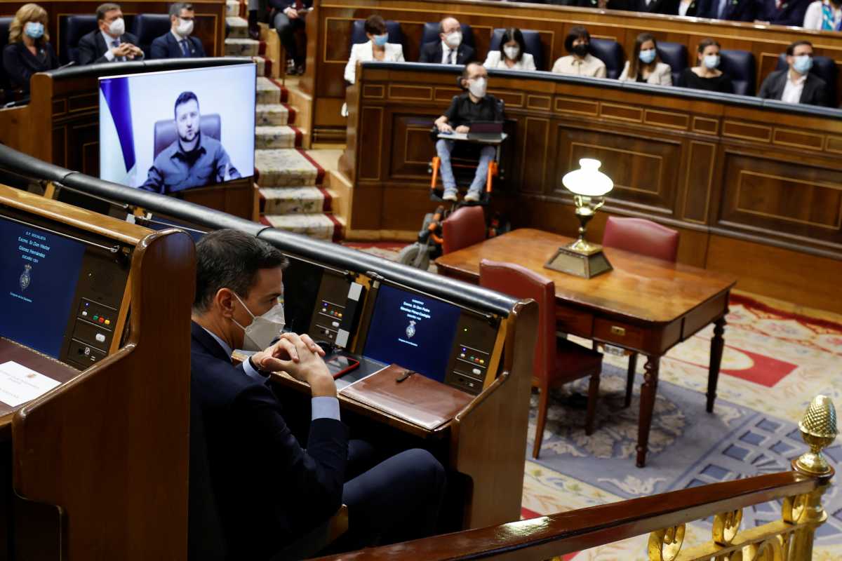 Spanish Prime Minister Pedro Sanchez sits as Ukrainian President Volodymyr Zelenskiy appears on a screen as he addresses members of Spanish parliament via video link, amid Russia's invasion of Ukraine, in Madrid, Spain, April 5, 2022. REUTERS