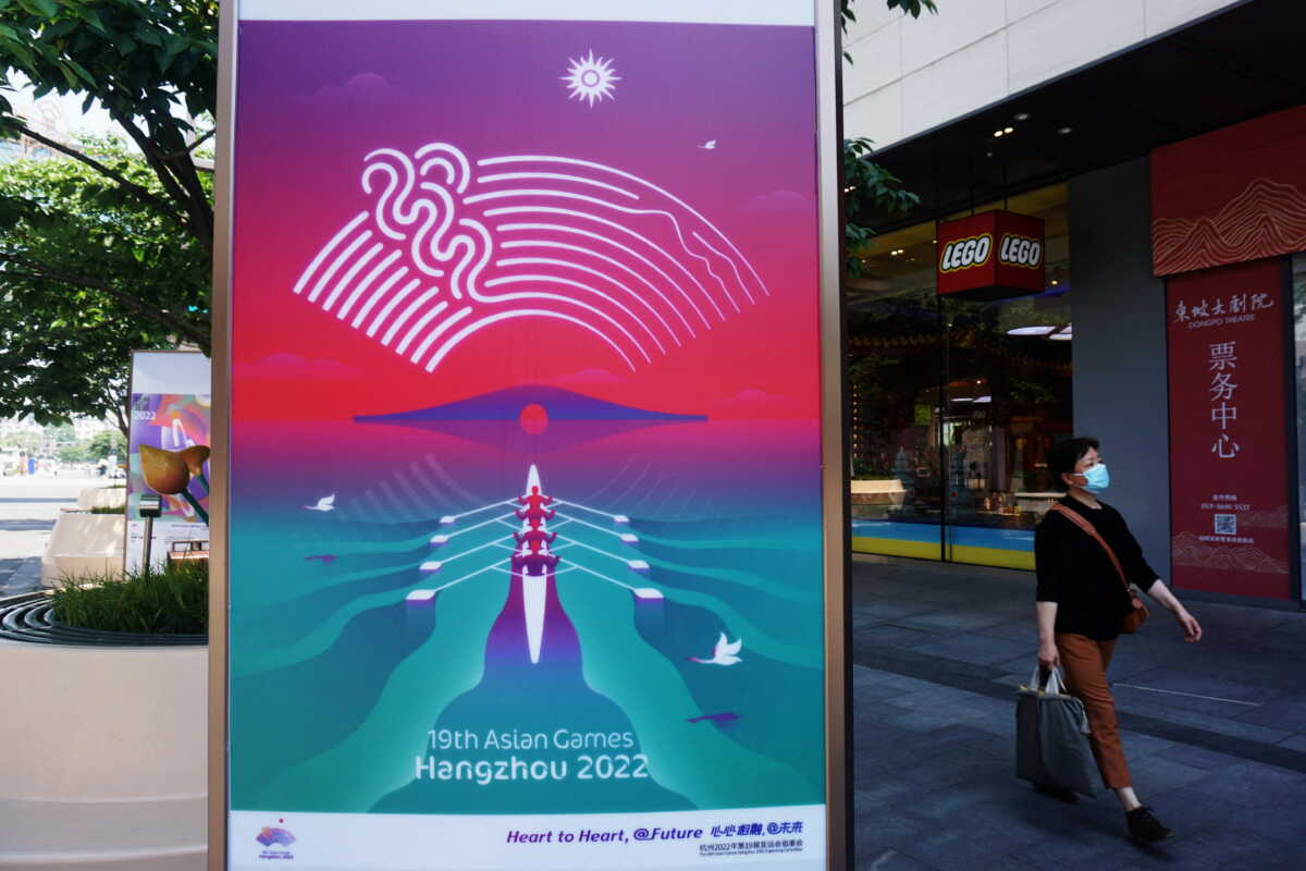 A person wearing a protective mask walks past a billboard for the 19th Asian Games Hangzhou 2022, amid the coronavirus disease (COVID-19) outbreak, in Hangzhou, Zhejiang province, China May 6, 2022.   China Daily via REUTERS ATTENTION EDITORS - THIS PICTURE WAS PROVIDED BY A THIRD PARTY. CHINA OUT. NO COMMERCIAL OR EDITORIAL SALES IN CHINA.