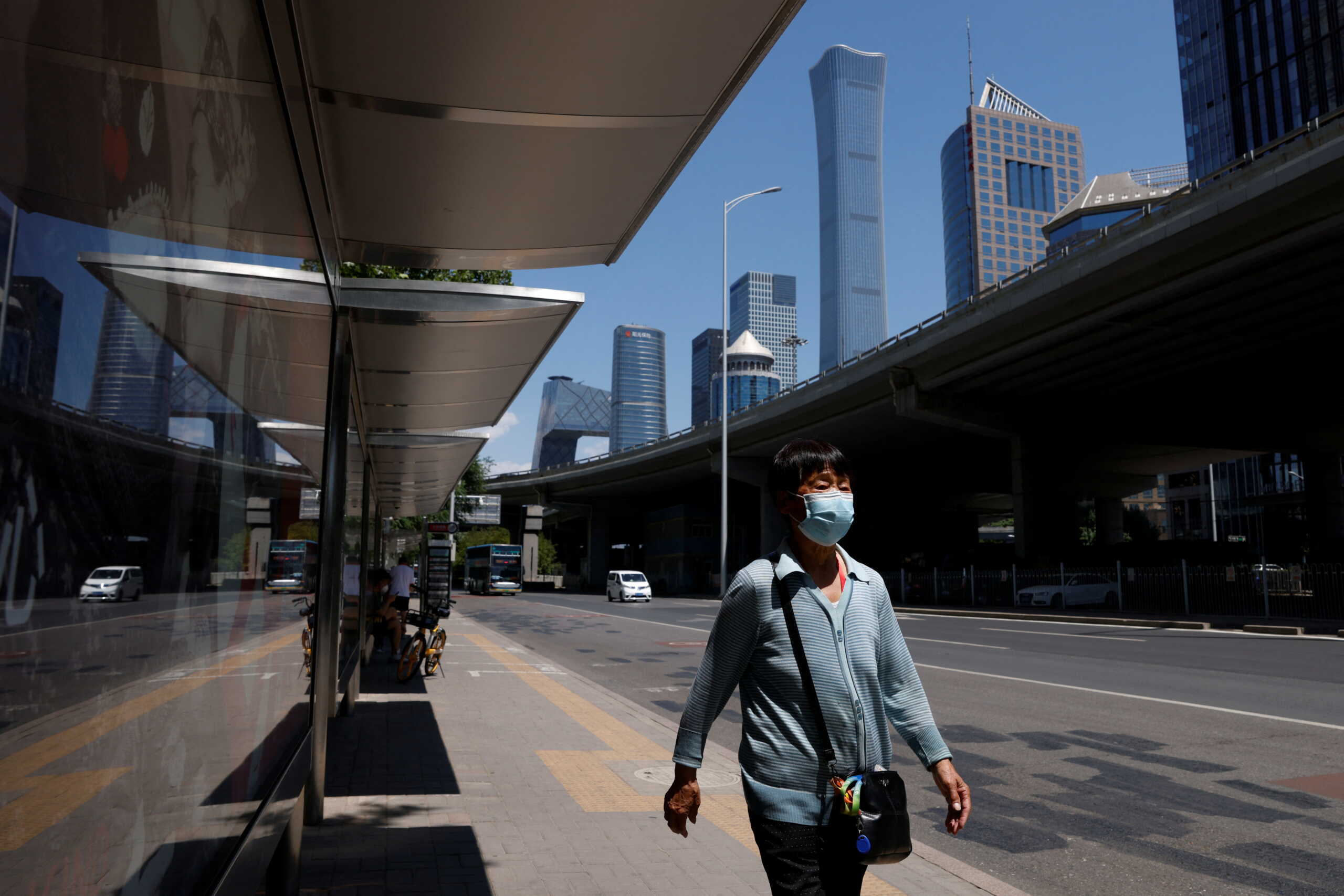 A woman wearing a face mask walks next to a bus stop in the Central Business District (CBD), amid the coronavirus disease (COVID-19) outbreak in Beijing, China May 30, 2022. REUTERS