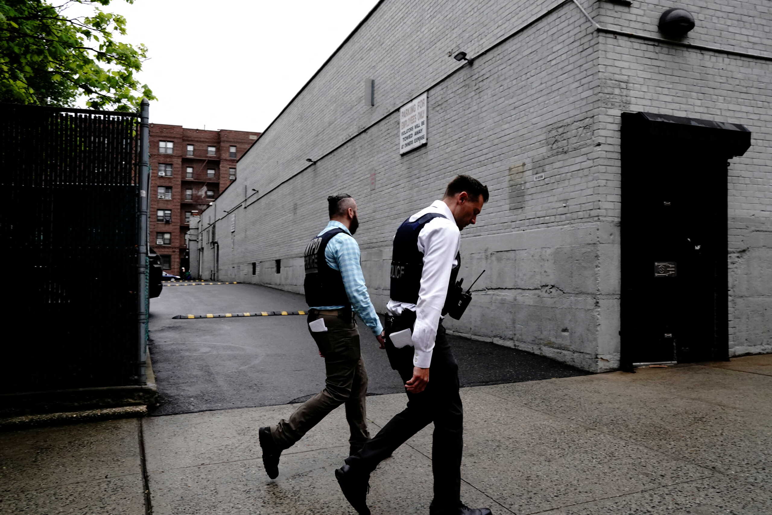 Officers of the New York City Police Department (NYPD) walk past the parking lot behind Great Wall, a Chinese restaurant where fatally shot and killed food delivery courier Zhiwen Yan worked, while investigating Yan?s shooting in Forest Hills, a neighbourhood in the Queens borough of New York City, U.S., May 2, 2022.