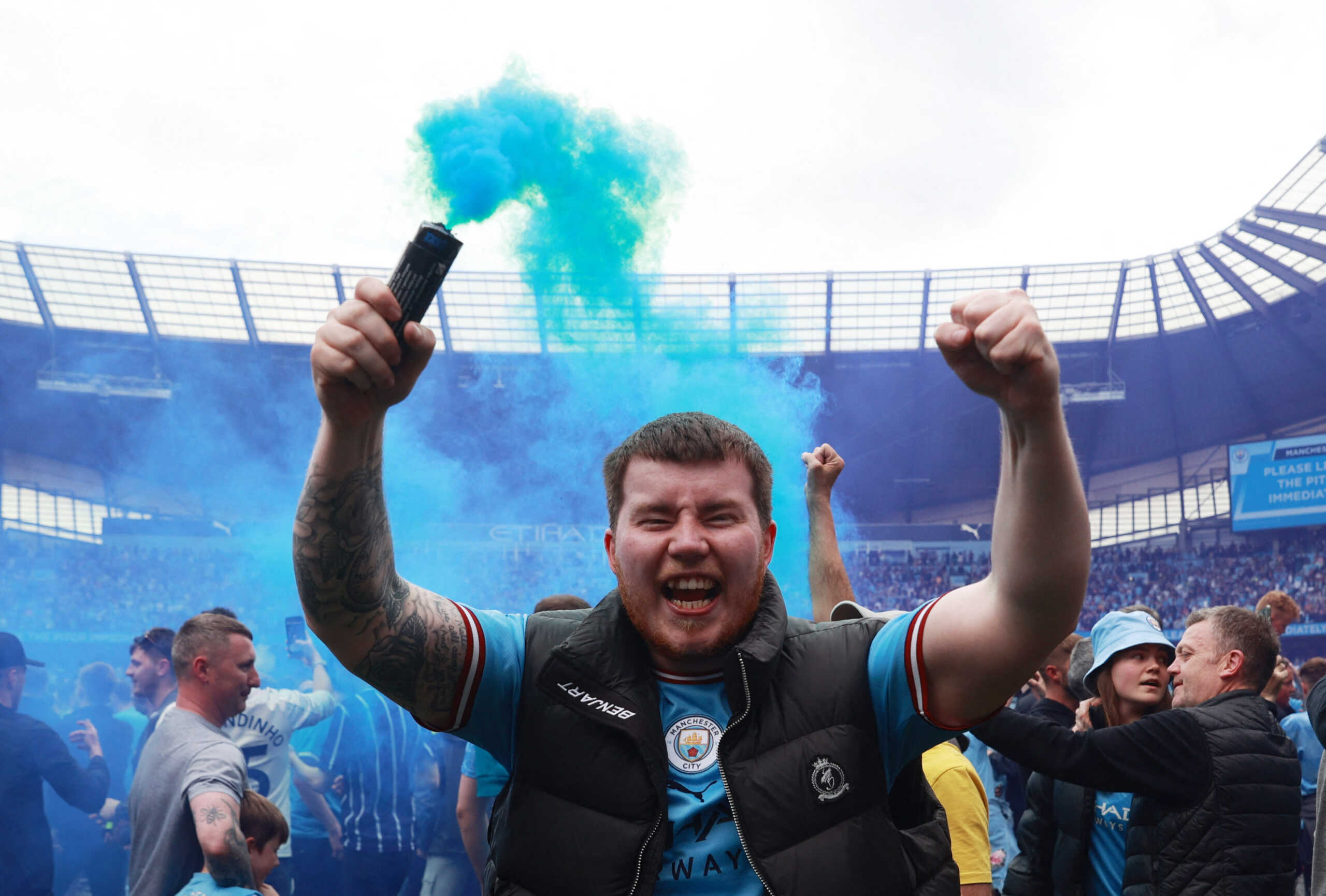 Soccer Football - Premier League - Manchester City v Aston Villa - Etihad Stadium, Manchester, Britain - May 22, 2022 Manchester City fan celebrates with a flare on the pitch after winning the Premier League REUTERS