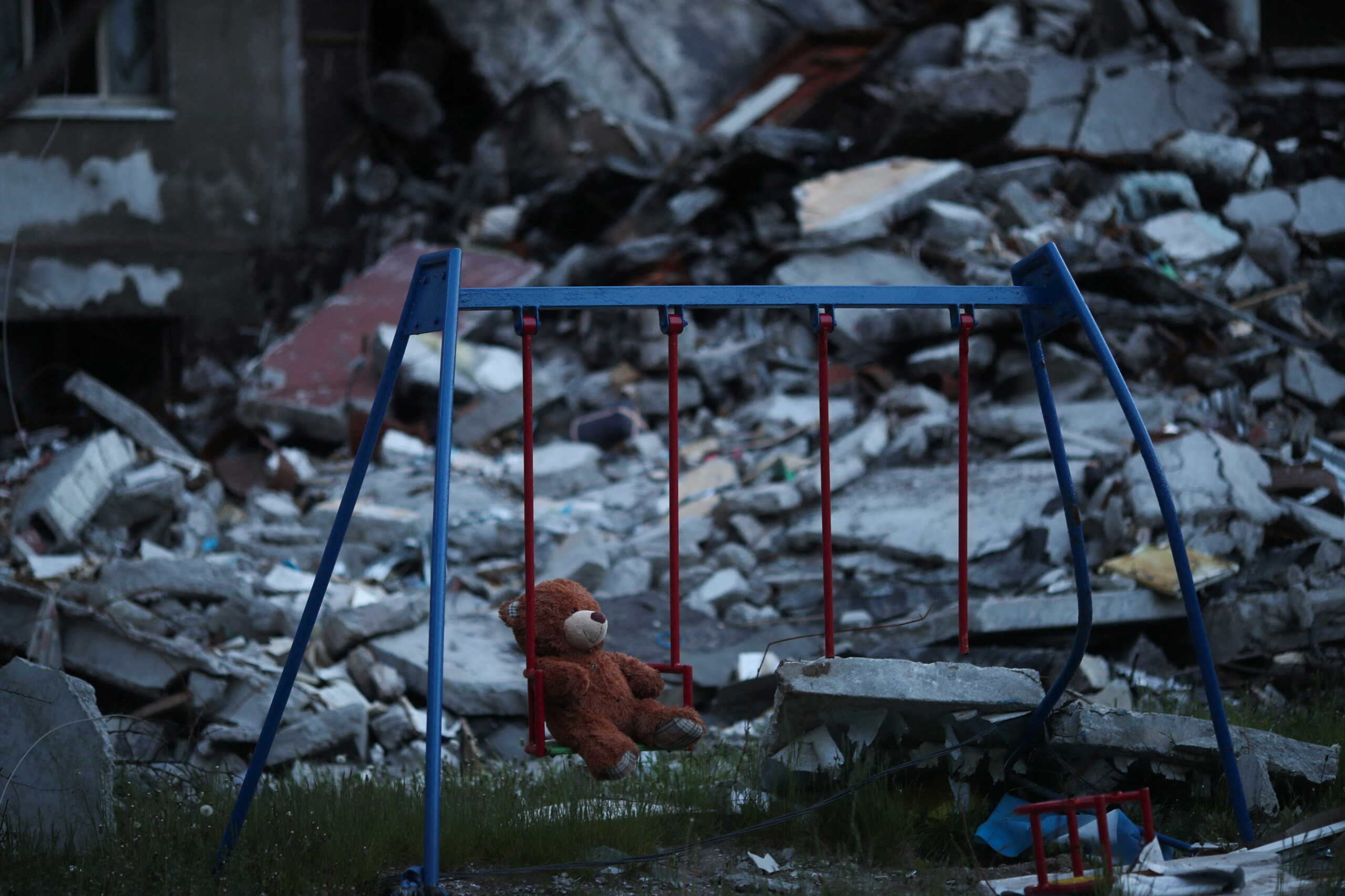 A teddy bear hangs on a swing next to a damaged building in Saltivka district, amid Russia's attack on Ukraine, in Kharkiv, Ukraine, May 17, 2022. REUTERS