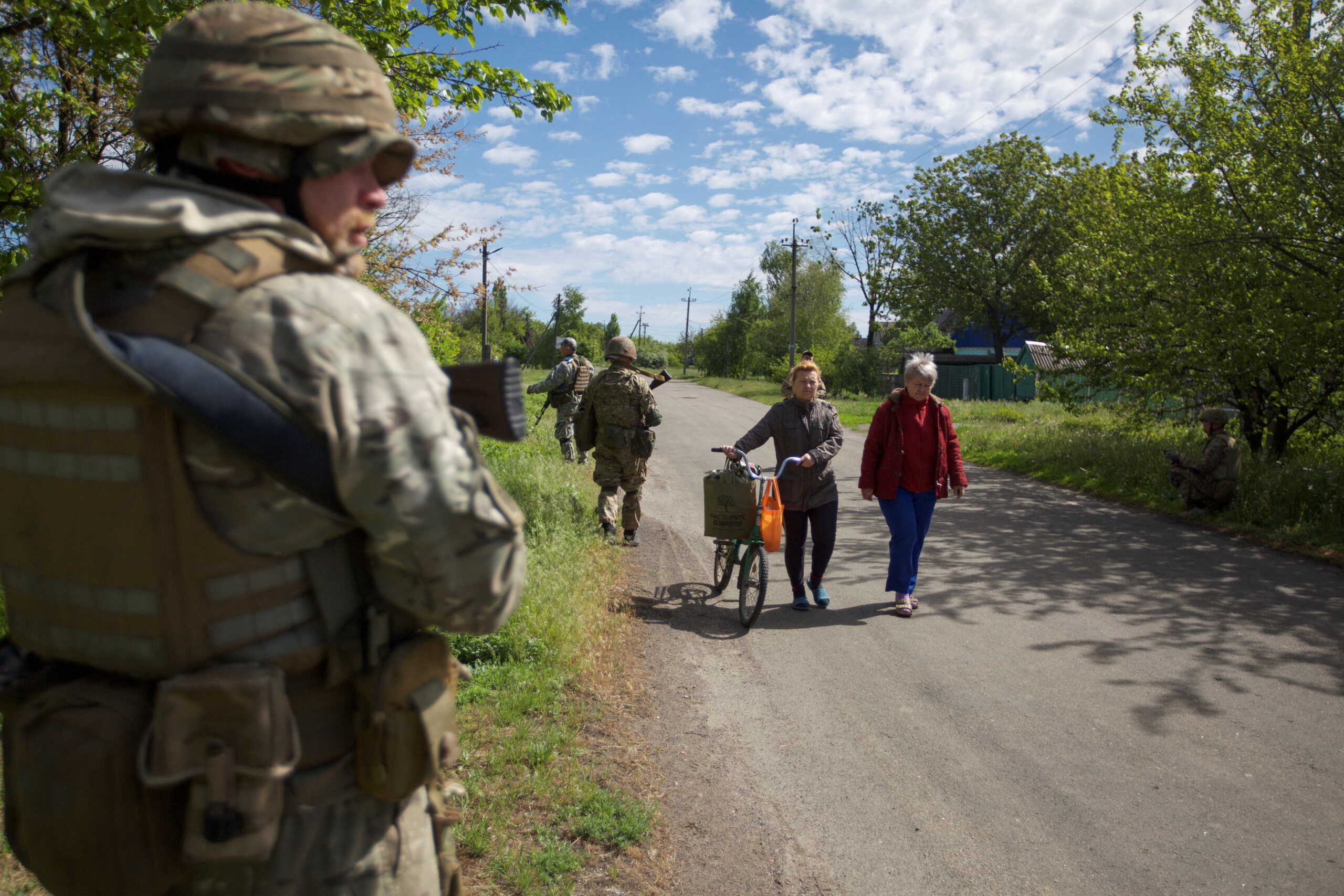 Local women walk along a street while Ukrainian servicemen patrol an area, as Russia's attack on Ukraine continues, in the town of Kurakhove, in Donetsk region, Ukraine May 20, 2022. Picture taken May 20, 2022.  REUTERS