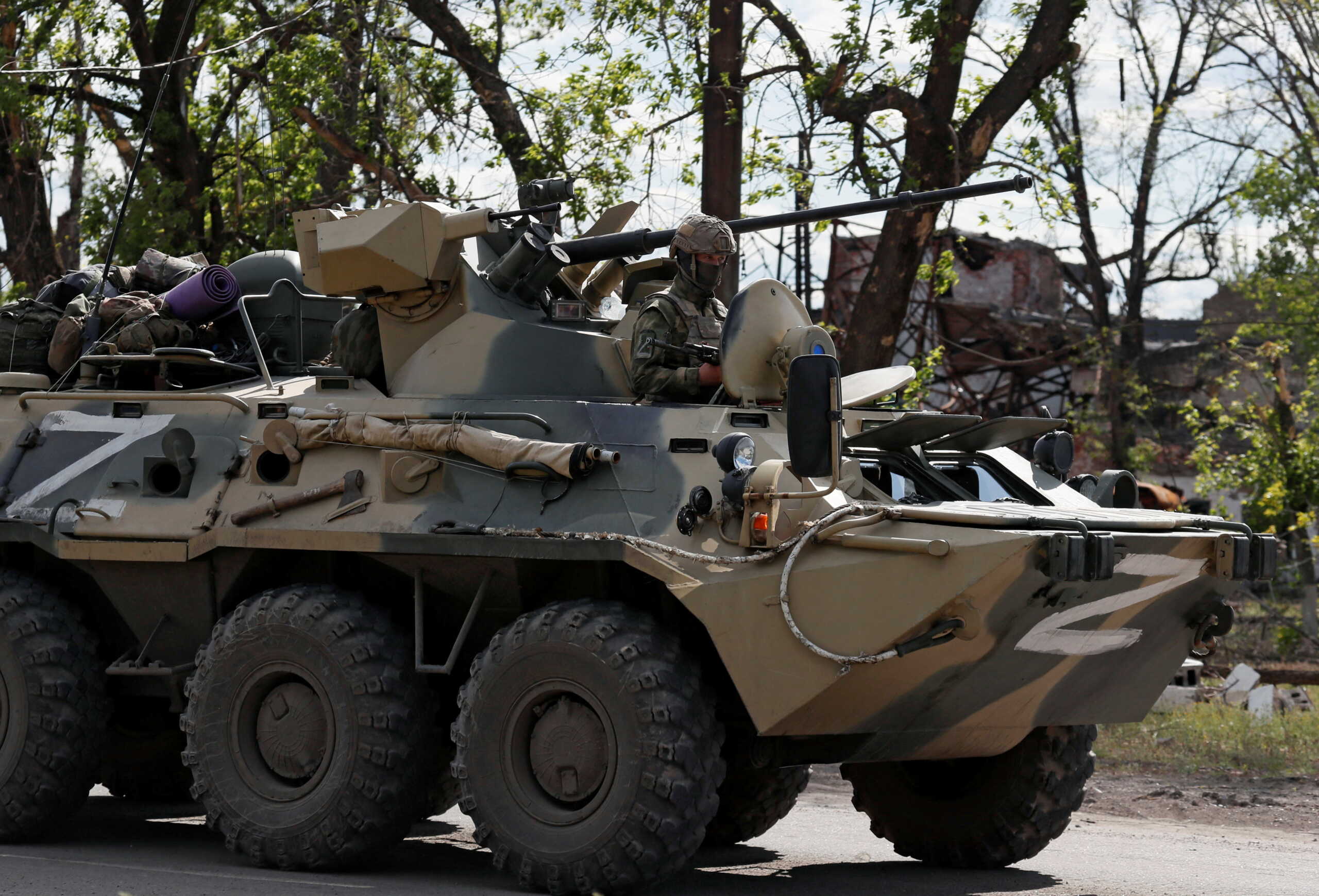 A service member of pro-Russian troops rides an armoured personnel carrier escorting buses with service members of Ukrainian forces who have surrendered after weeks holed up at Azovstal steel works in the course of Ukraine-Russia conflict in Mariupol, Ukraine May 17, 2022. REUTERS