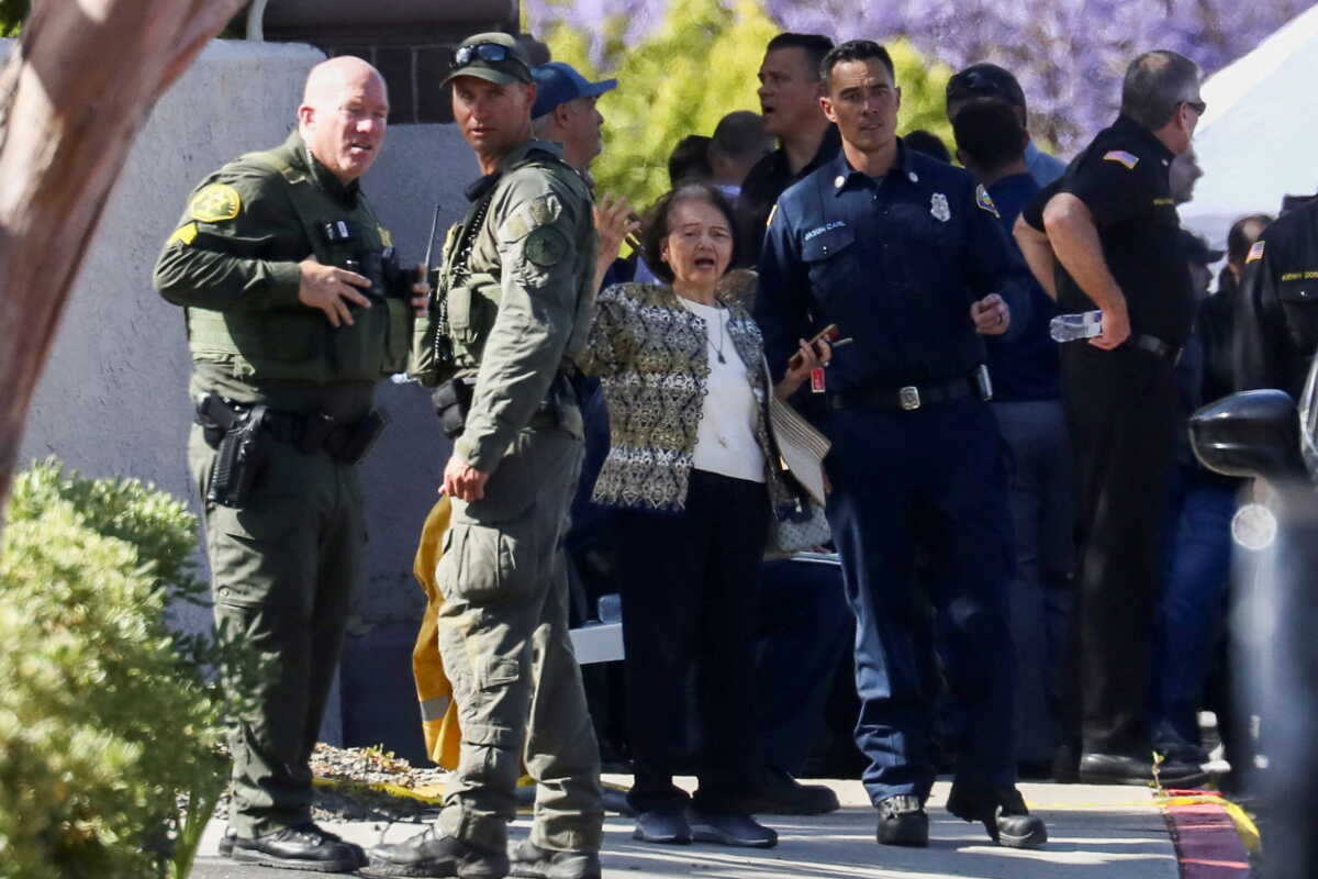 A woman reacts next to law enforcement officers after a deadly gunfire erupted at Geneva Presbyterian Church in Laguna Woods, California, U.S. May 15, 2022.  REUTERS