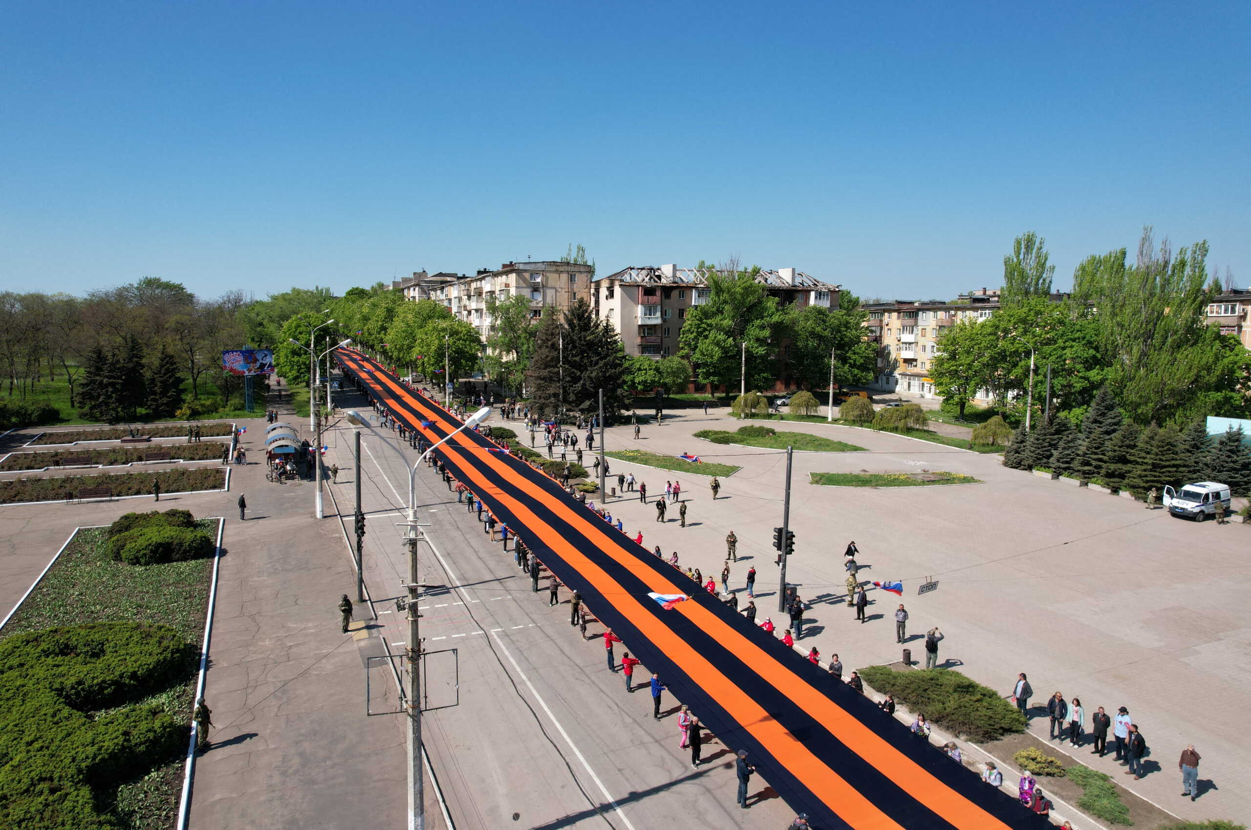 Participants hold a giant St. George's Ribbon during a ceremony, marking the 77th anniversary of the victory over Nazi Germany in World War Two, in the course of Ukraine-Russia conflict in the southern port city of Mariupol, Ukraine May 9, 2022. Picture taken with a drone. REUTERS