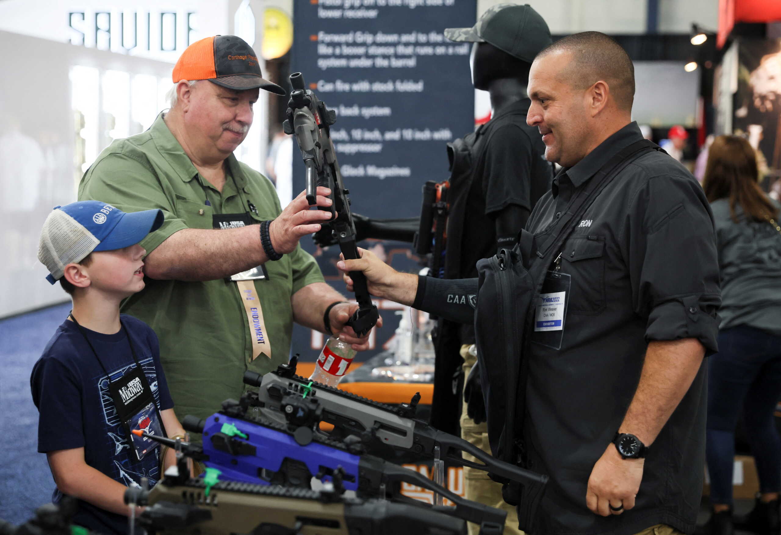 A man holds a pistol conversion kit as a child watches during the National Rifle Association (NRA) annual convention in Houston, Texas, U.S. May 27, 2022. REUTERS