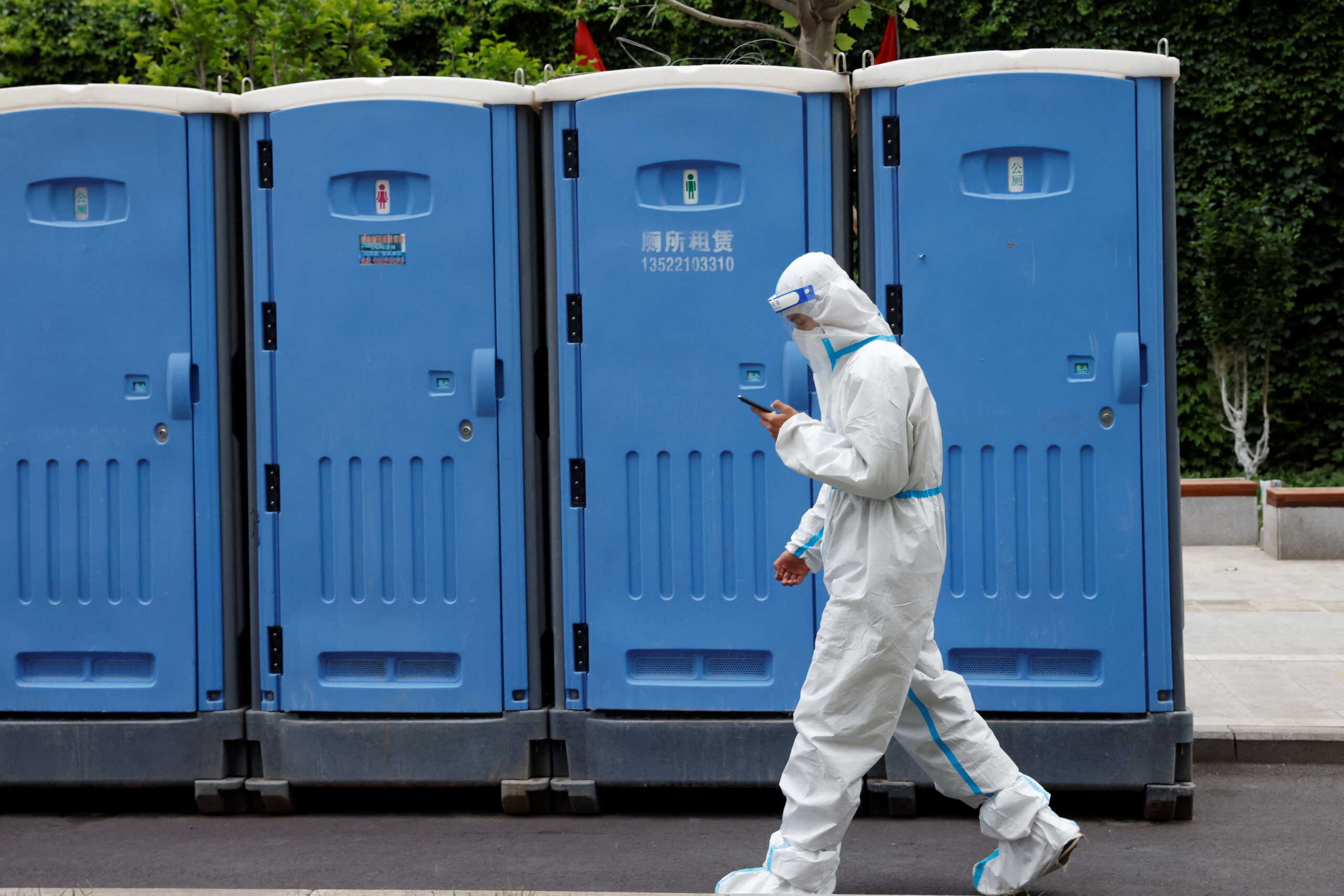 A worker in a protective suit walks past mobile toilets near an area under lockdown, amid the coronavirus disease (COVID-19) outbreak in Beijing, China May 12, 2022. REUTERS