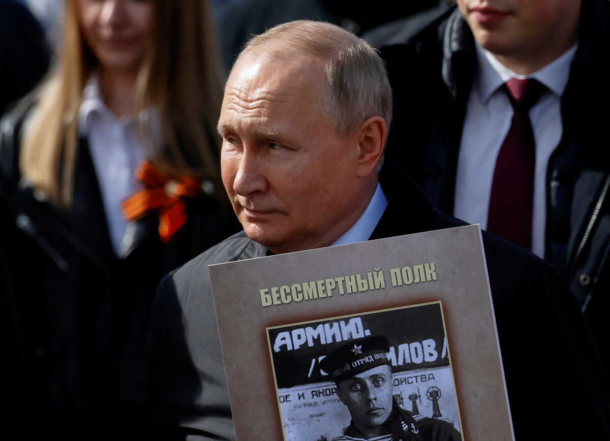 Russian President Vladimir Putin holds a portrait of his father, war veteran Vladimir Spiridonovich Putin, as he takes part in the Immortal Regiment march on Victory Day, which marks the 77th anniversary of the victory over Nazi Germany in World War Two, in central Moscow, Russia May 9, 2022. REUTERS