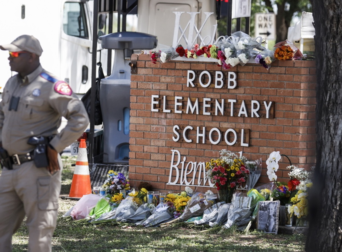 epa09976024 Texas Highway Patrol officers stand near a memorial of flowers at the scene of a mass shooting at the Robb Elementary School in Uvalde, Texas, USA, 25 May 2022. According to Texas officials, at least 19 children and two adults were killed in the shooting. The eighteen-year-old gunman was killed by responding officers.  EPA
