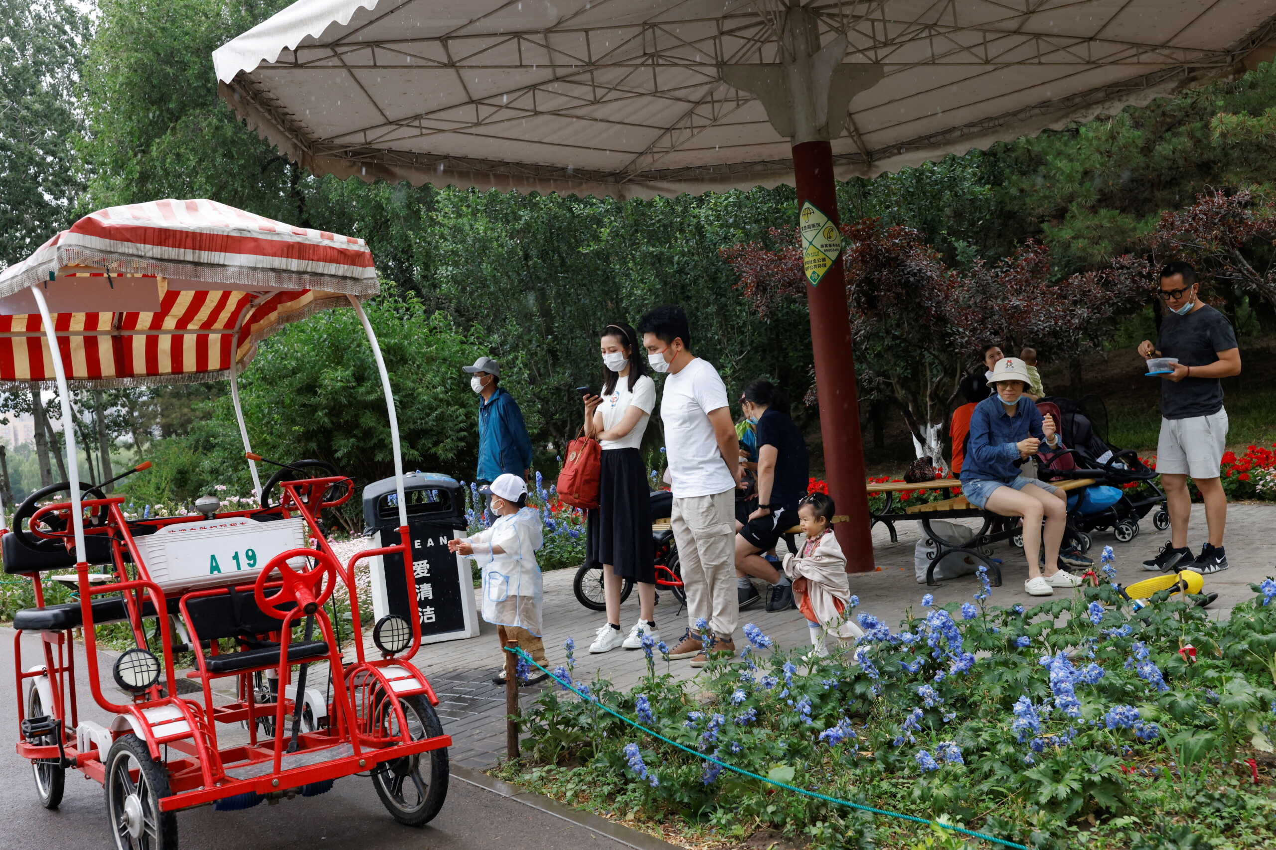 People take cover from rain at Sun Park on the day of its reopening after the government eased some of the restrictions, amid the coronavirus disease (COVID-19) outbreak in Beijing, China May 29, 2022. REUTERS