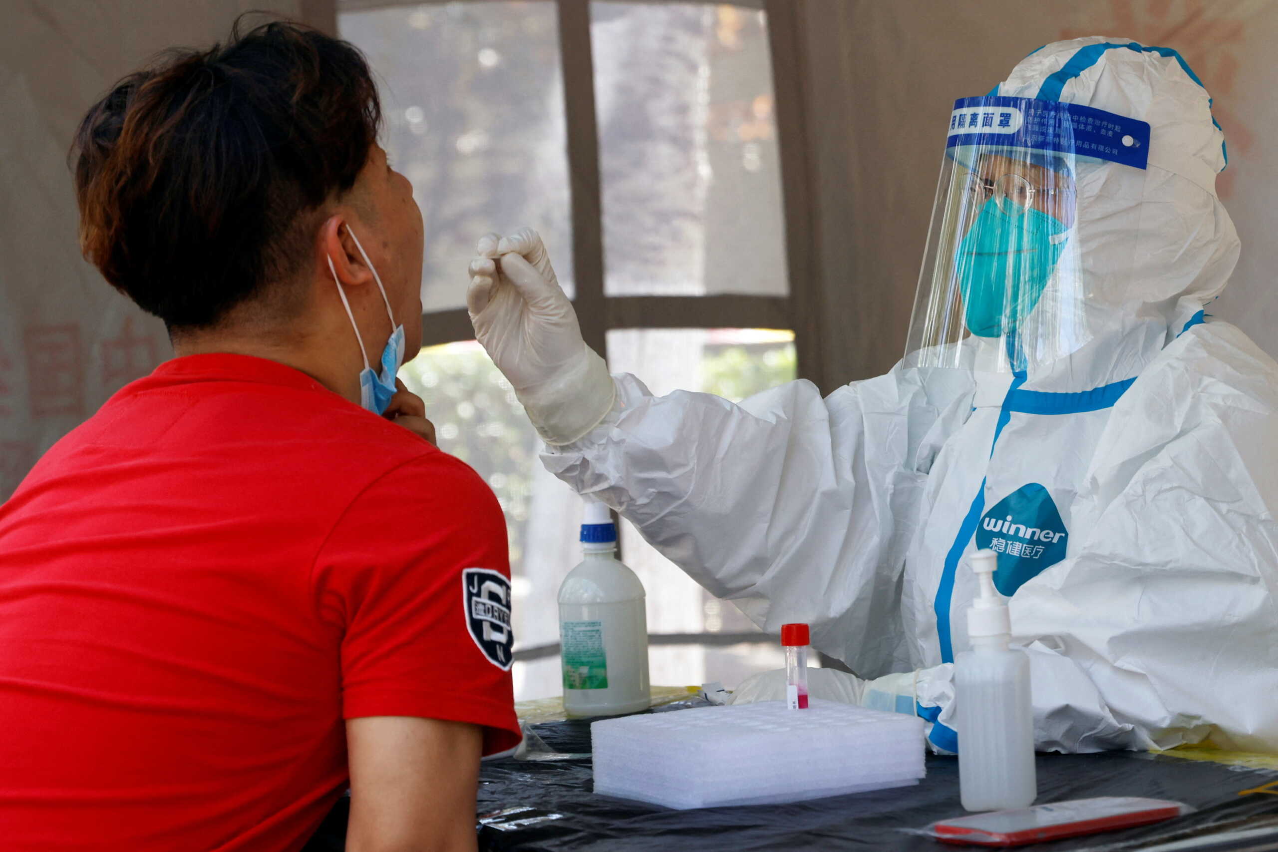 A medical worker in a protective suit collects a swab from a resident at a makeshift nucleic acid testing site amid the coronavirus disease (COVID-19) outbreak in Beijing, China May 25, 2022. REUTERS