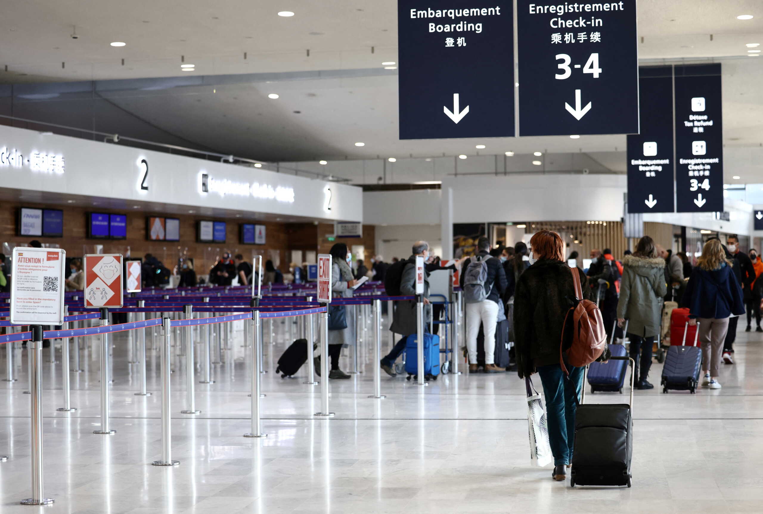 FILE PHOTO: Passengers walk in the departures area of the Terminal 2 at Paris Charles de Gaulle airport in Roissy-en-France near Paris, France, December 2, 2021. REUTERS