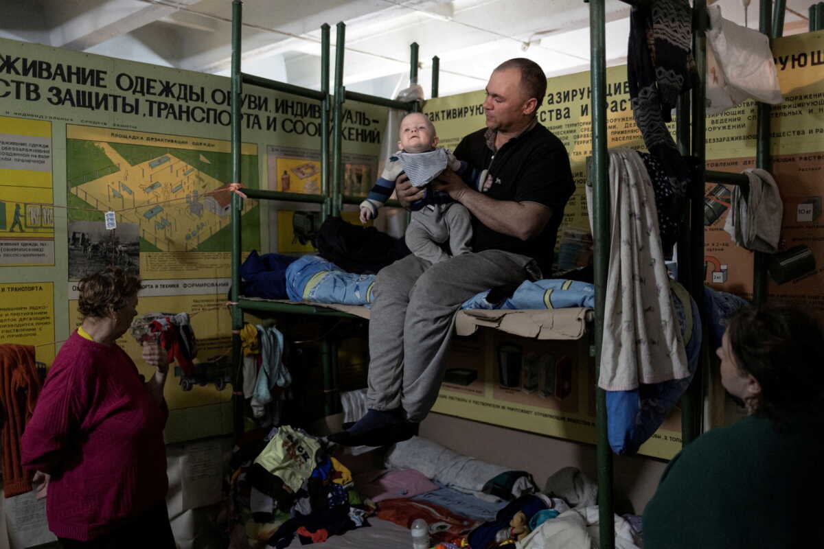 FILE PHOTO: A man holds his baby inside Azot chemical plant's bomb shelter, where people have been hiding from from shelling since the beginning of the war, in Sievierodonetsk, Luhansk region, Ukraine, April 16, 2022. REUTERS