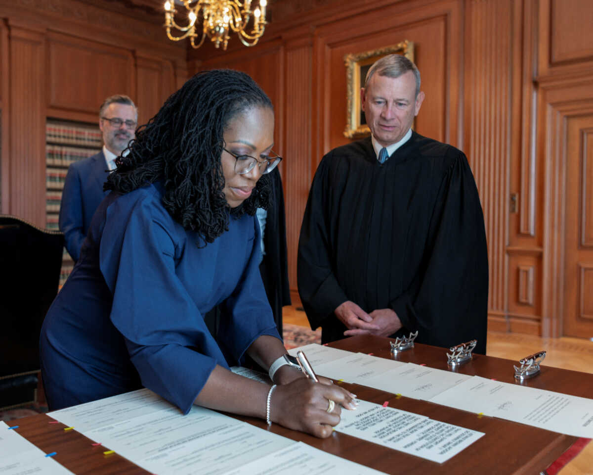 Justice Ketanji Brown Jackson signs her oaths of office as her husband Patrick and U.S. Supreme Court Chief Justice John Roberts look on after she took her oaths of office as an Associate Justice of the U.S. Supreme Court in a handout image provided by the U.S. Supreme Court from ceremonies held in the Justices' Conference Room at the Supreme Court building in Washington, U.S., June 30, 2022. Fred Schilling