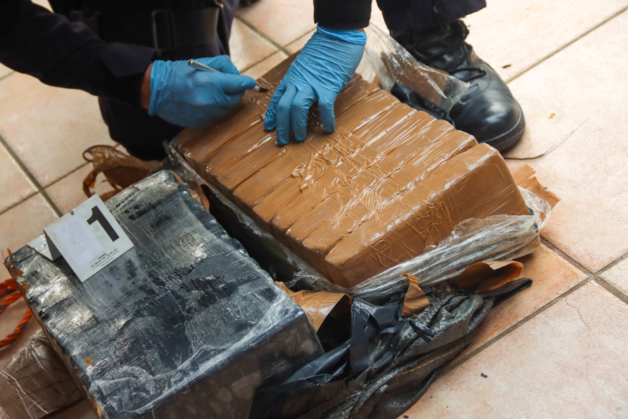 A police officer checks a seized shipment which, according to the National Civil Police, contains 810 kg (1785 lbs) of cocaine in a low profile vessel, in La Concordia, El Salvador, in this picture provided to Reuters May 18, 2022. El Salvador's Presidency