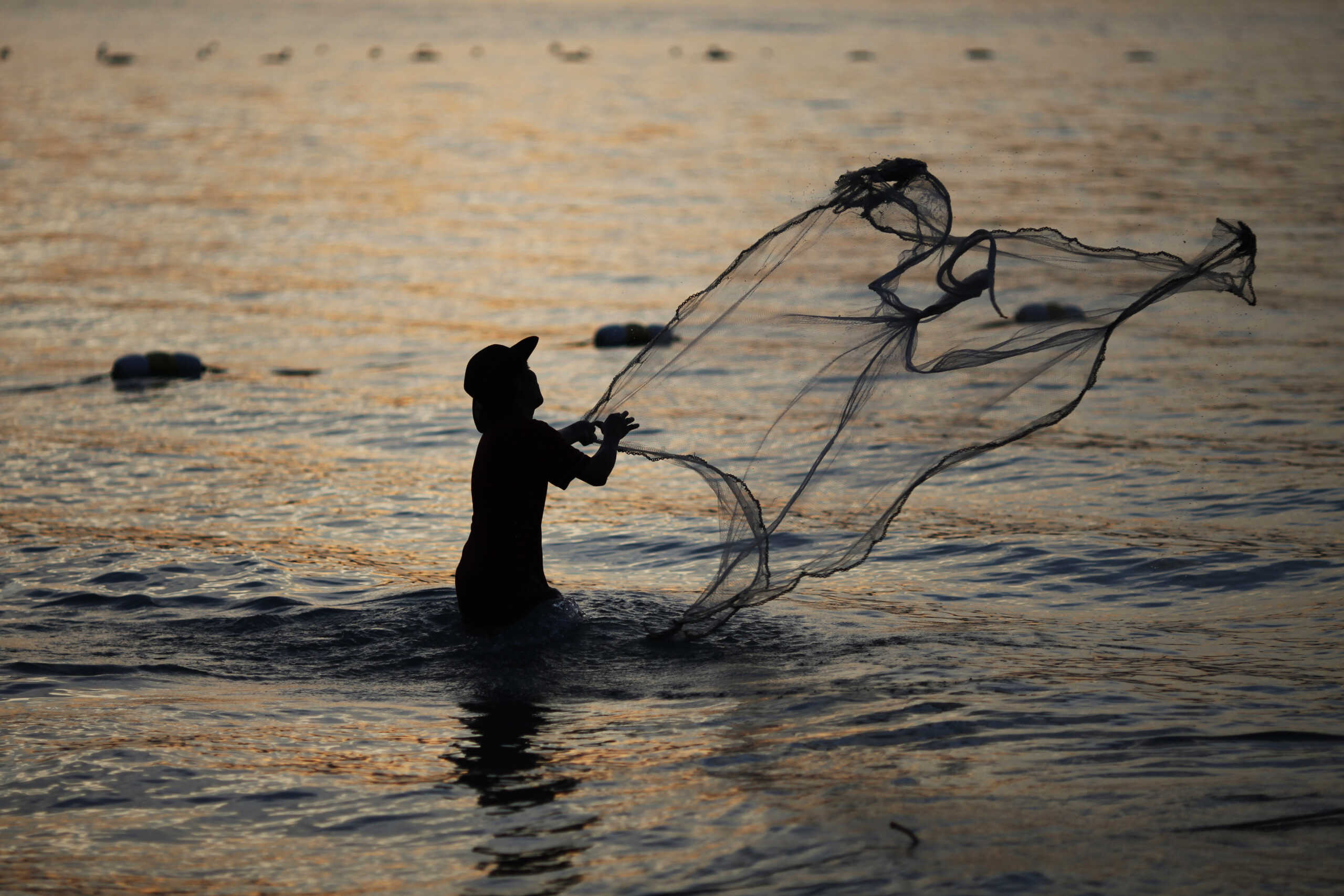 A Thai fisherman casts his net at Patong beach in Phuket, one of Asia's premier resort islands December 10, 2009. As the world prepares to mark the fifth anniversary of the tsunami that killed 226,000 people in 13 Asian and African countries, scars have yet to heal even after homes have been rebuilt, tourists have returned and foreign aid has ended. Picture taken December 10, 2009. REUTERS
