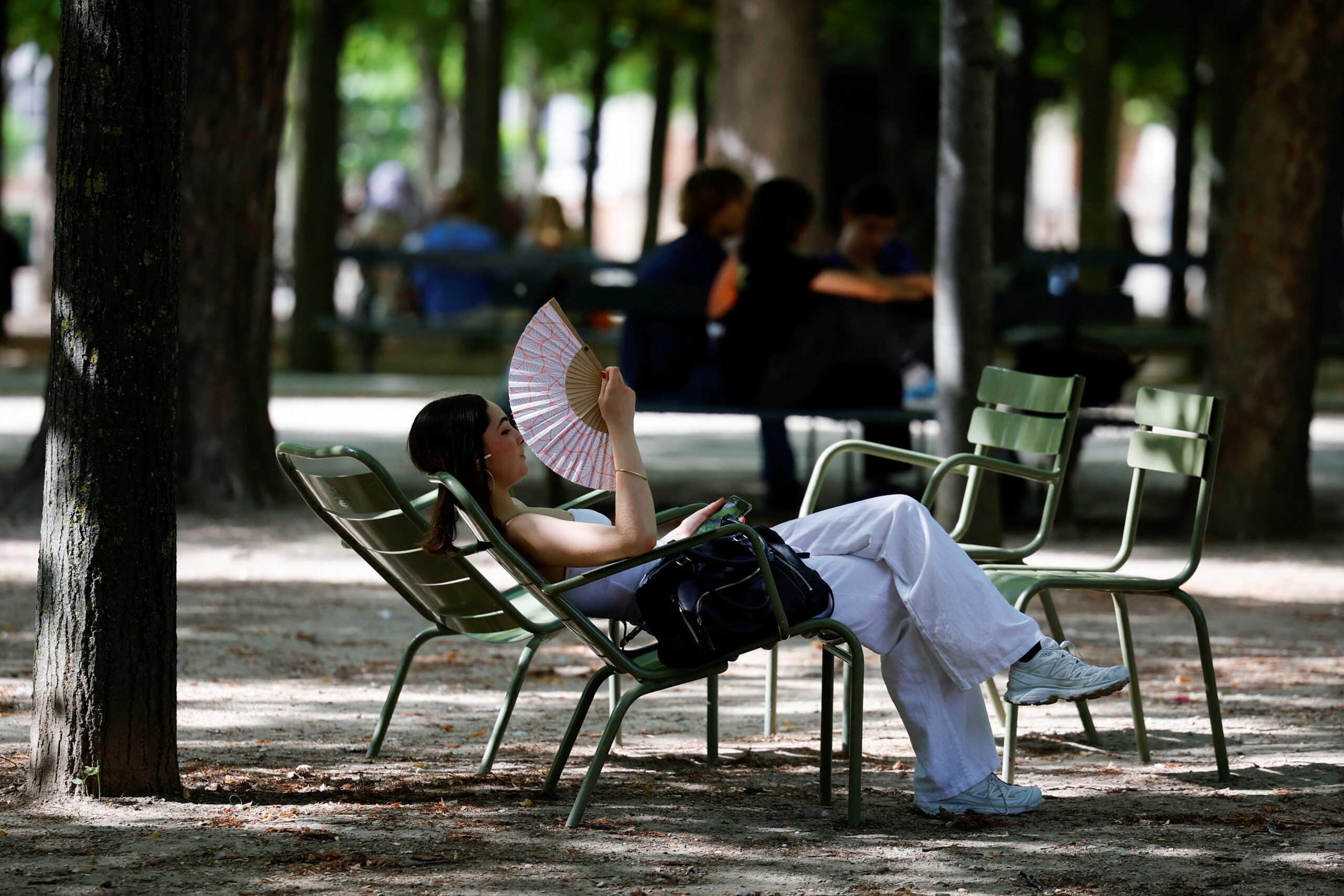 A woman uses a fan to cool down at the Luxembourg Gardens as an early heatwave hits the country, in Paris, France June 17, 2022. REUTERS